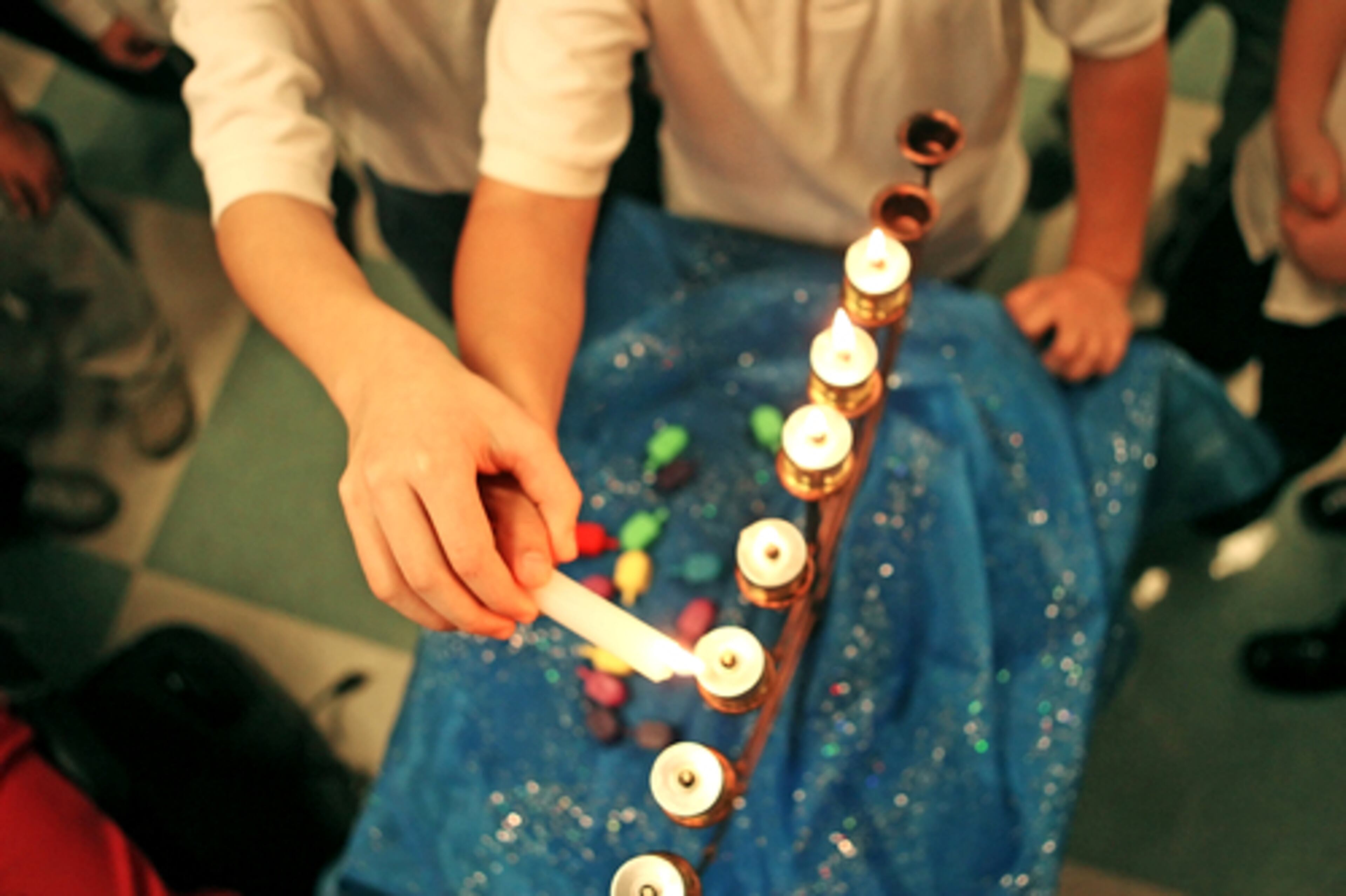 One part of the celebration is lighting candles of a special candelabra, or Menorah, representing each of the eight nights. Two children from the Torah Day School kids' choir light the Menorah marking the sixth night of Hanukkah.