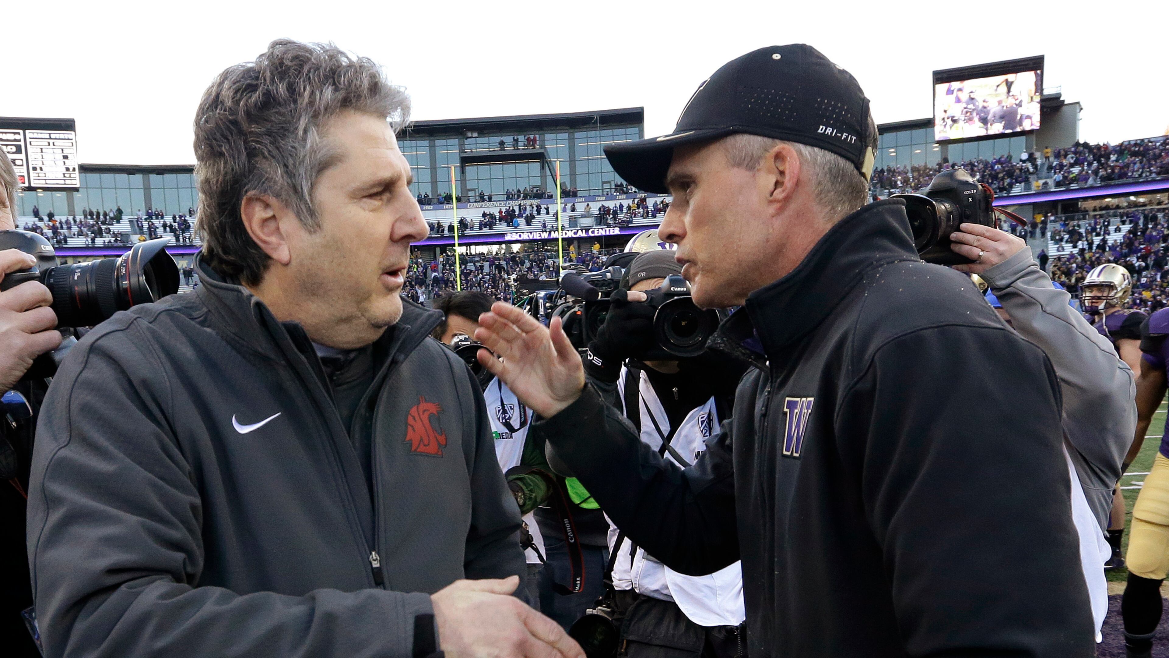 FILE - In this Nov. 27, 2015, file photo, Washington State coach Mike Leach, left, is greeted by Washington coach Chris Petersen after an NCAA college football game in Seattle. Rarely have both teams entered the Apple Cup with so much at stake. (AP Photo/Elaine Thompson, File)