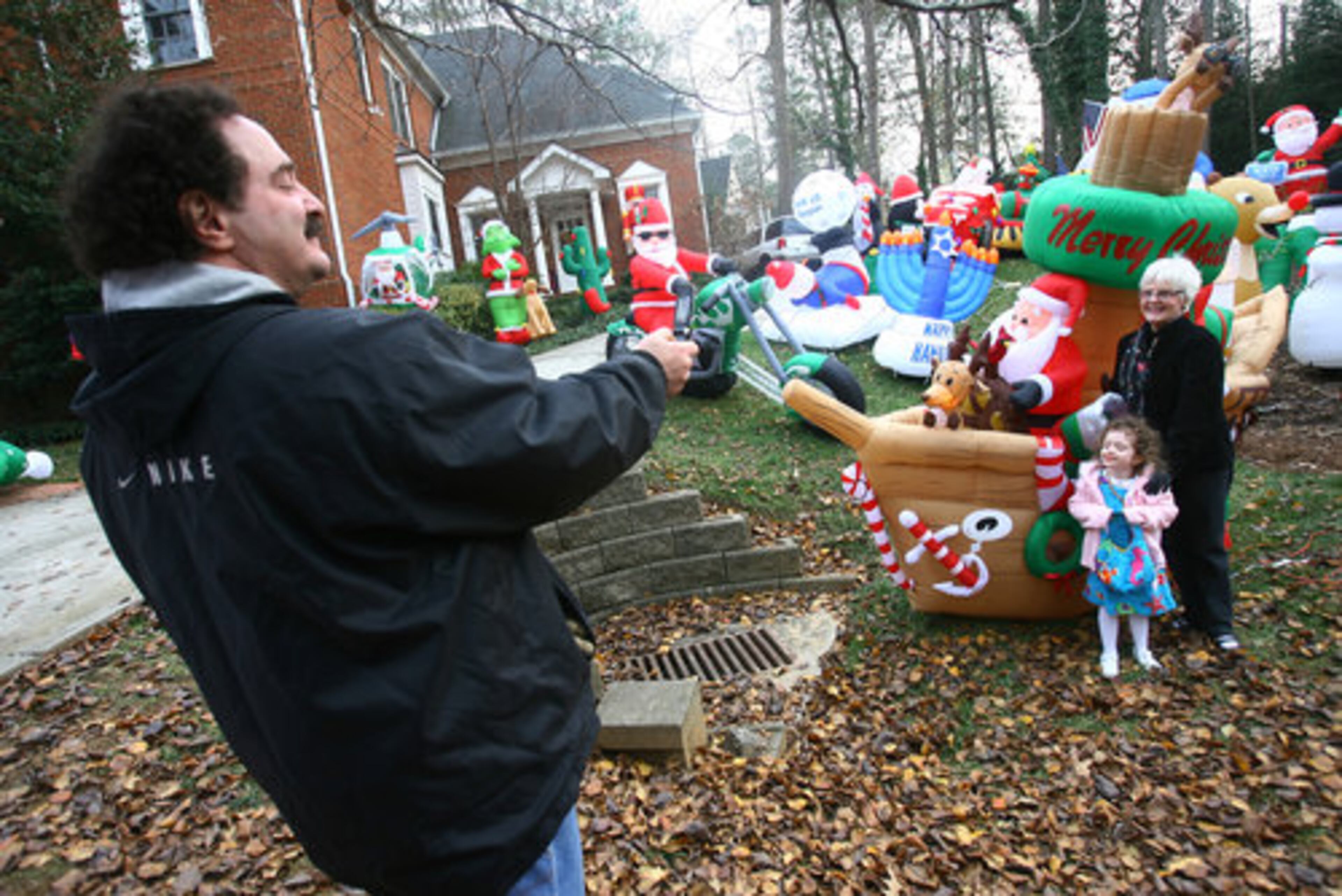 Gropper, seen here taking a cell phone photo of visitors, doesn't mind the attention. One of his favorite inflatables: an airplane piloted by Santa Claus that features an animated spinning propeller.