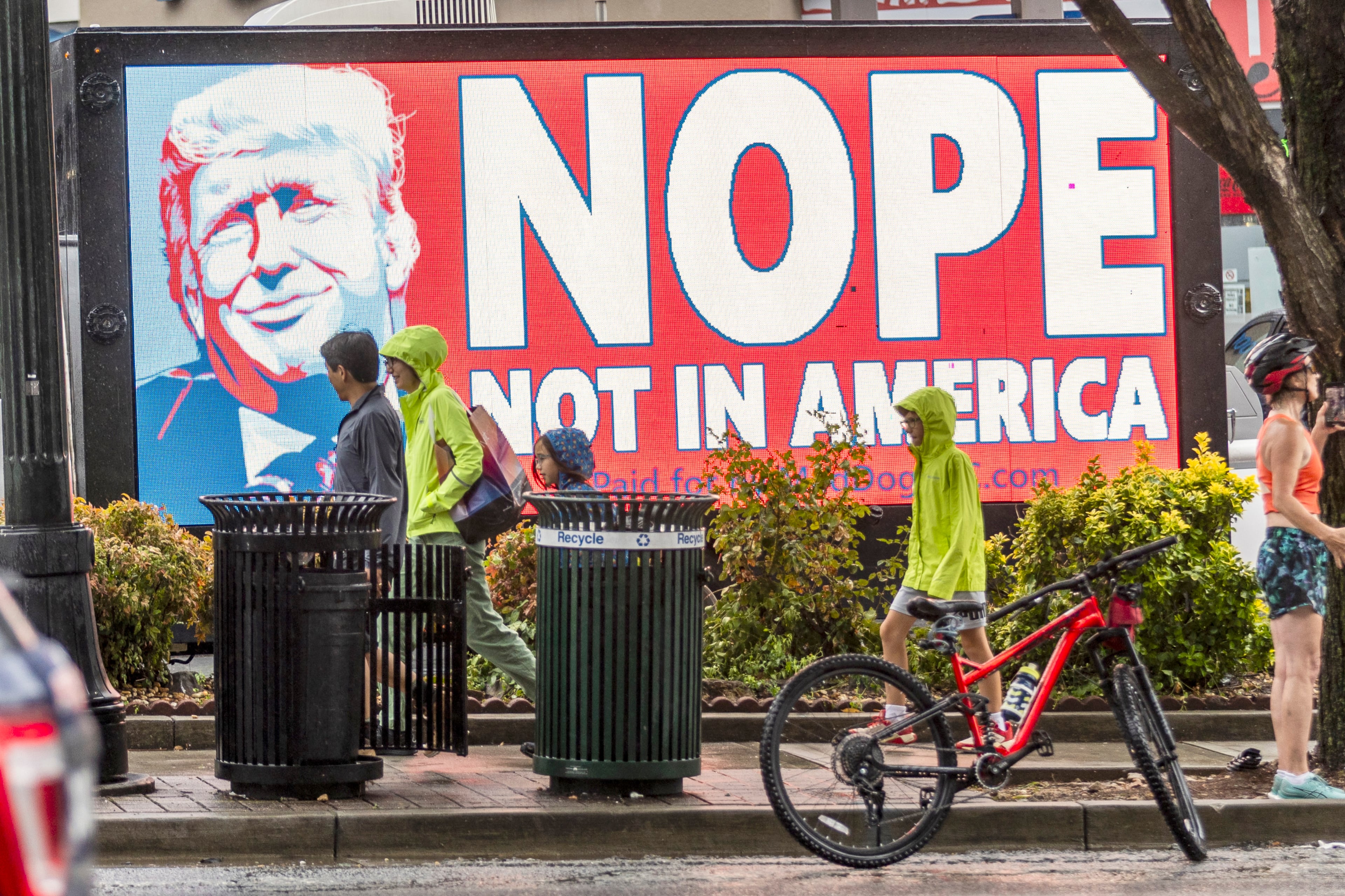 People walk by a mobile sign truck on 10th Street near the Trump/Biden Debate site in Atlanta on Thursday, June 27, 2024. (Steve Schaefer / AJC)