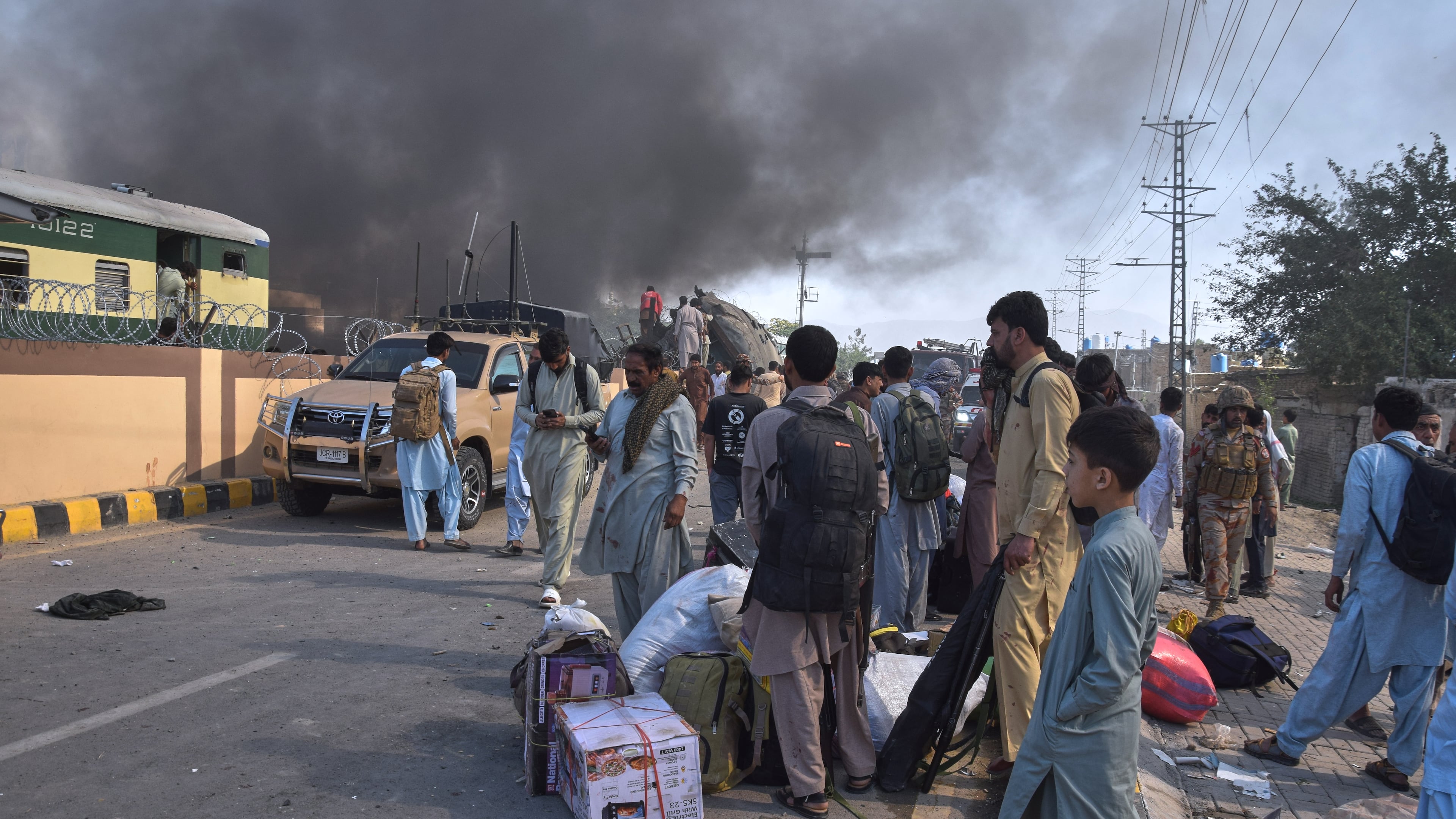 Volunteers look for victims from an overturned train coach on a railway track as survivors wait for transport at the site of bomb explosion, in Quetta, Pakistan, Sunday, May 24, 2026. (AP Photo/Arshad Butt)