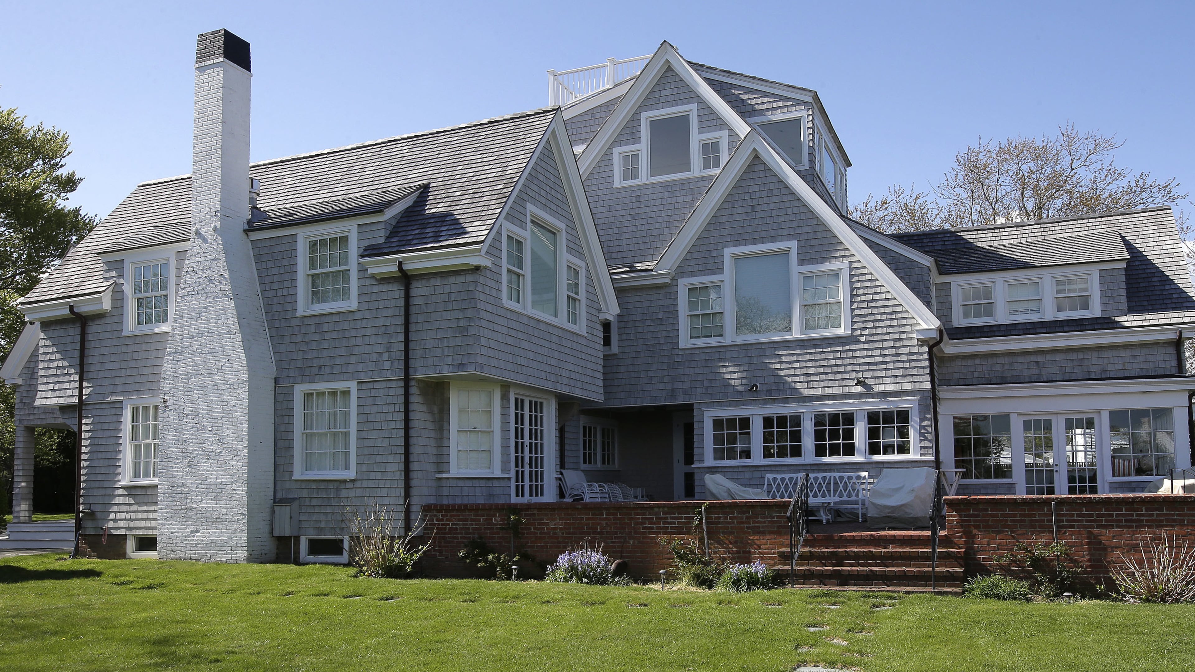 In this Monday, May 8, 2017 photo, a house that was once the residence of President John F. Kennedy is surrounded by trees in Hyannis Port, Mass. Pieces of the home can now be called pieces of art. Floorboards, window panes, light fixtures, copper pipes, shingles, faded wallpaper, rusted nails and even a metal hook that once held a porch swing are among ordinary items salvaged during an overhaul of the president's former home on Cape Cod and transformed by local artists into mixed media artworks inspired by the president who was born 100 years ago this month. (AP Photo/Steven Senne)