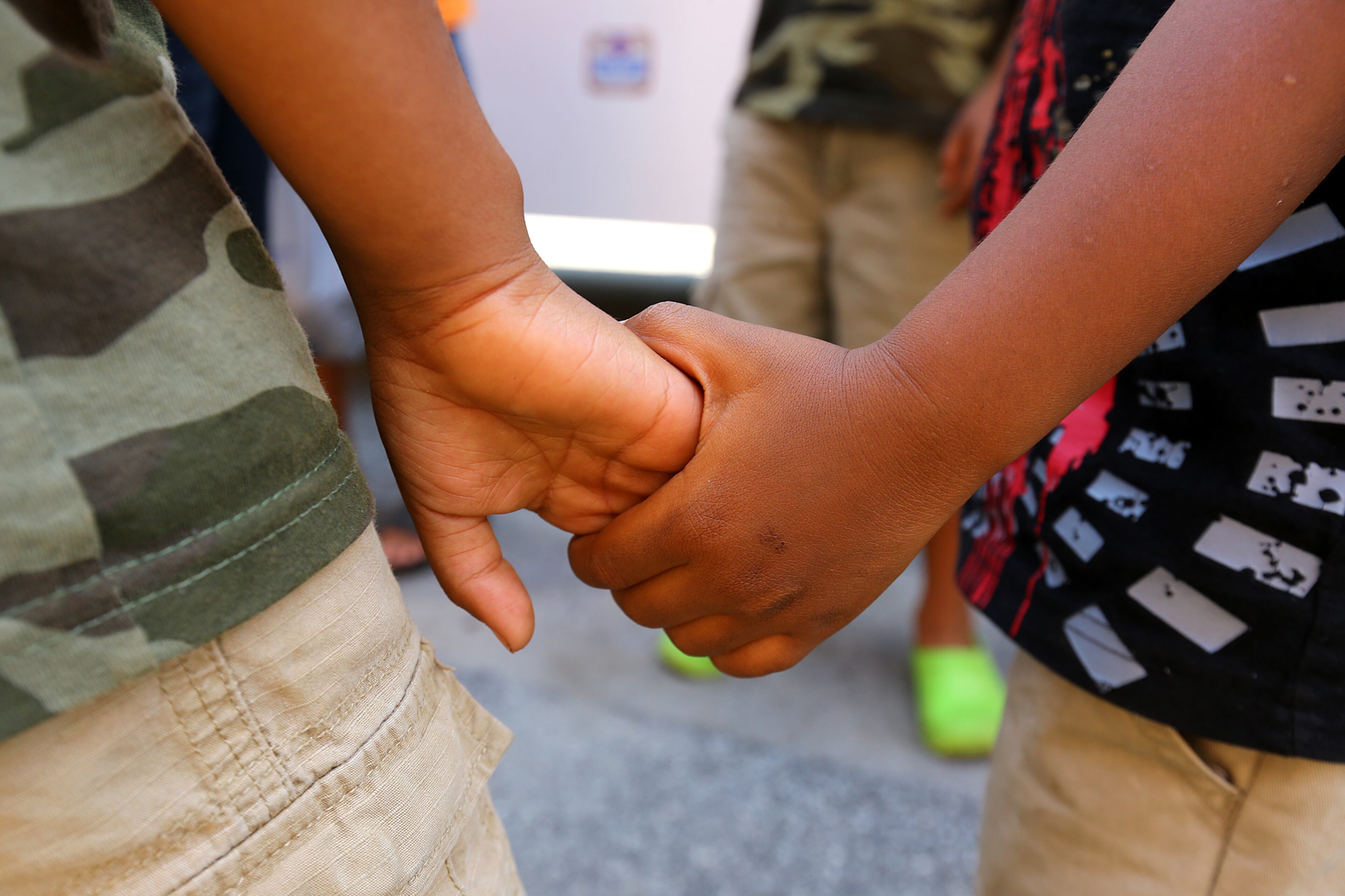 Elijah Eads (left), 5, holds hands with his brother Jaden Eads (right), 3, while they wait in line with their mother Chinon Durhan as needy families receive food items during the large feeding event "Feed the Children" at the City of Refuge on Thursday, June 19, 2014, in Atlanta. CURTIS COMPTON / CCOMPTON@AJC.COM