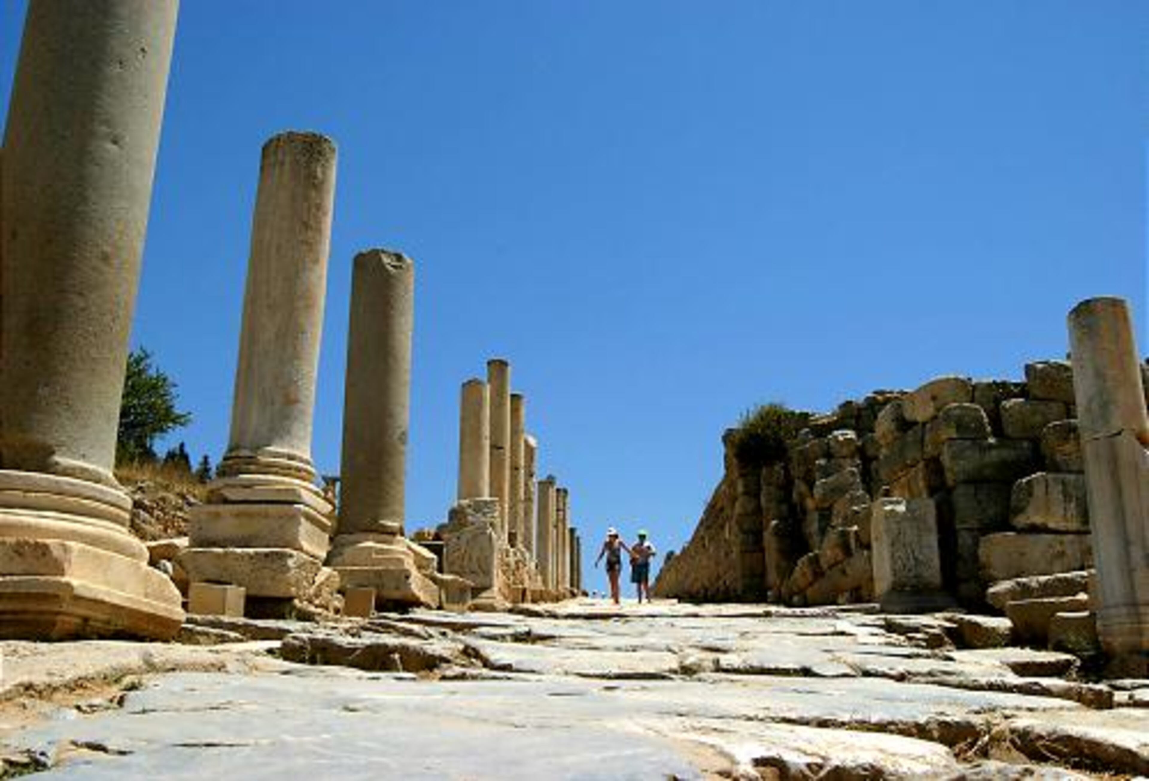Tourists walk along the road running through center of the ancient Roman ruins of Ephesus.