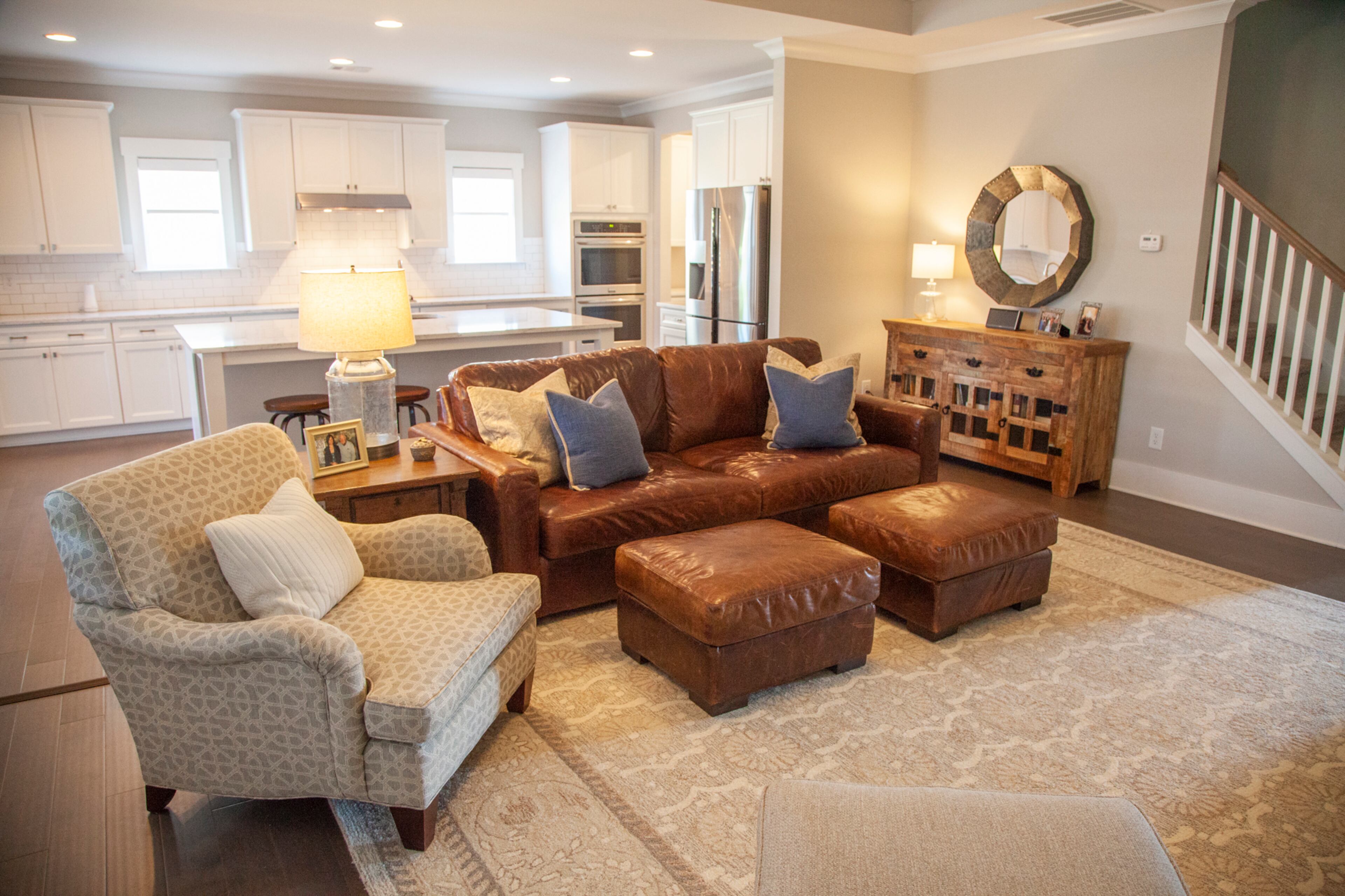 The kitchen is open to the den, which was an important factor for the homeowners. The leather couch is from RH and the rug is from Bassett. A sideboard and mirror connects the two spaces.