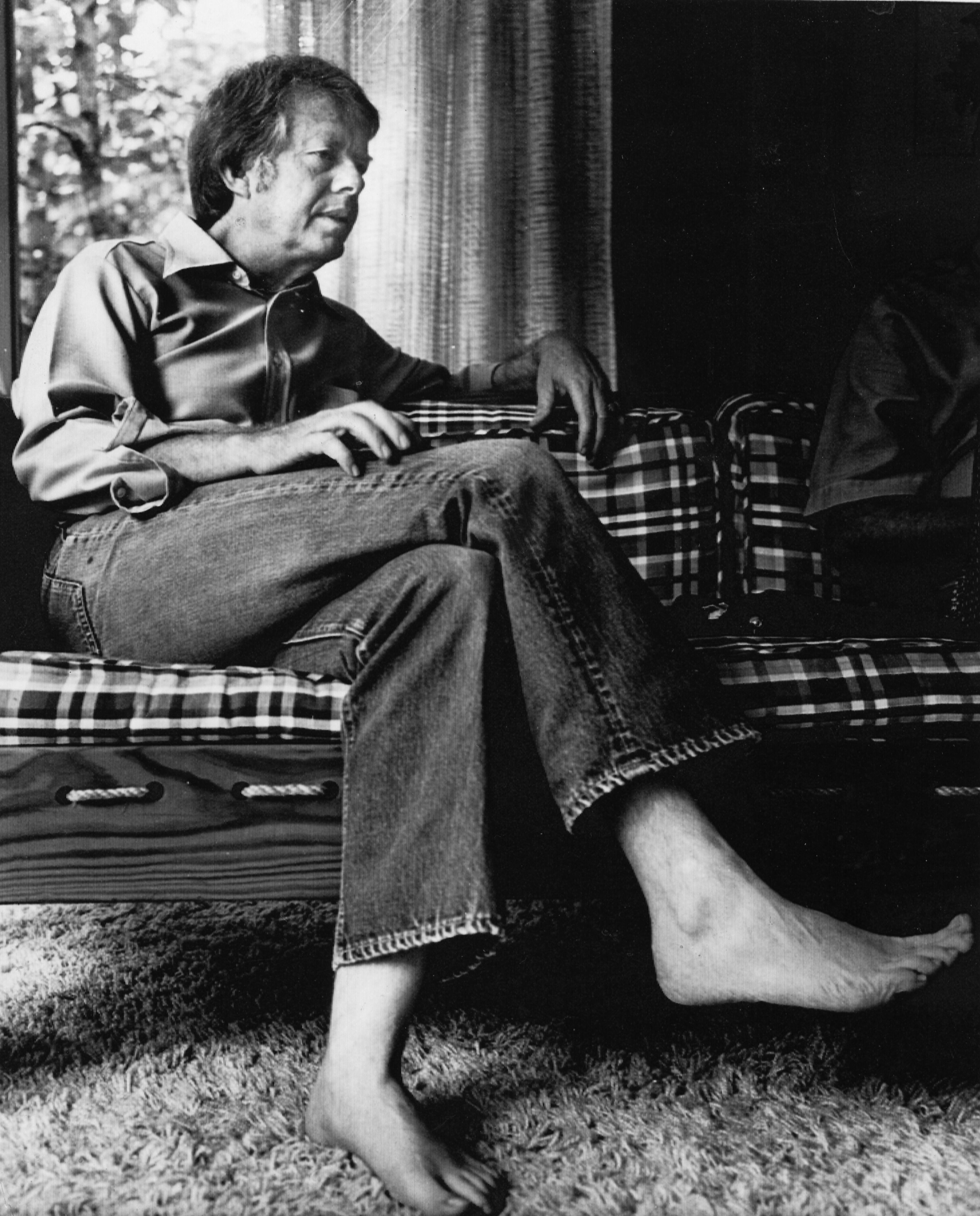 Jimmy Carter, wearing jeans and barefooted, talks with reporters in his home in Plains, during his run for president in 1976. (Associated Press)