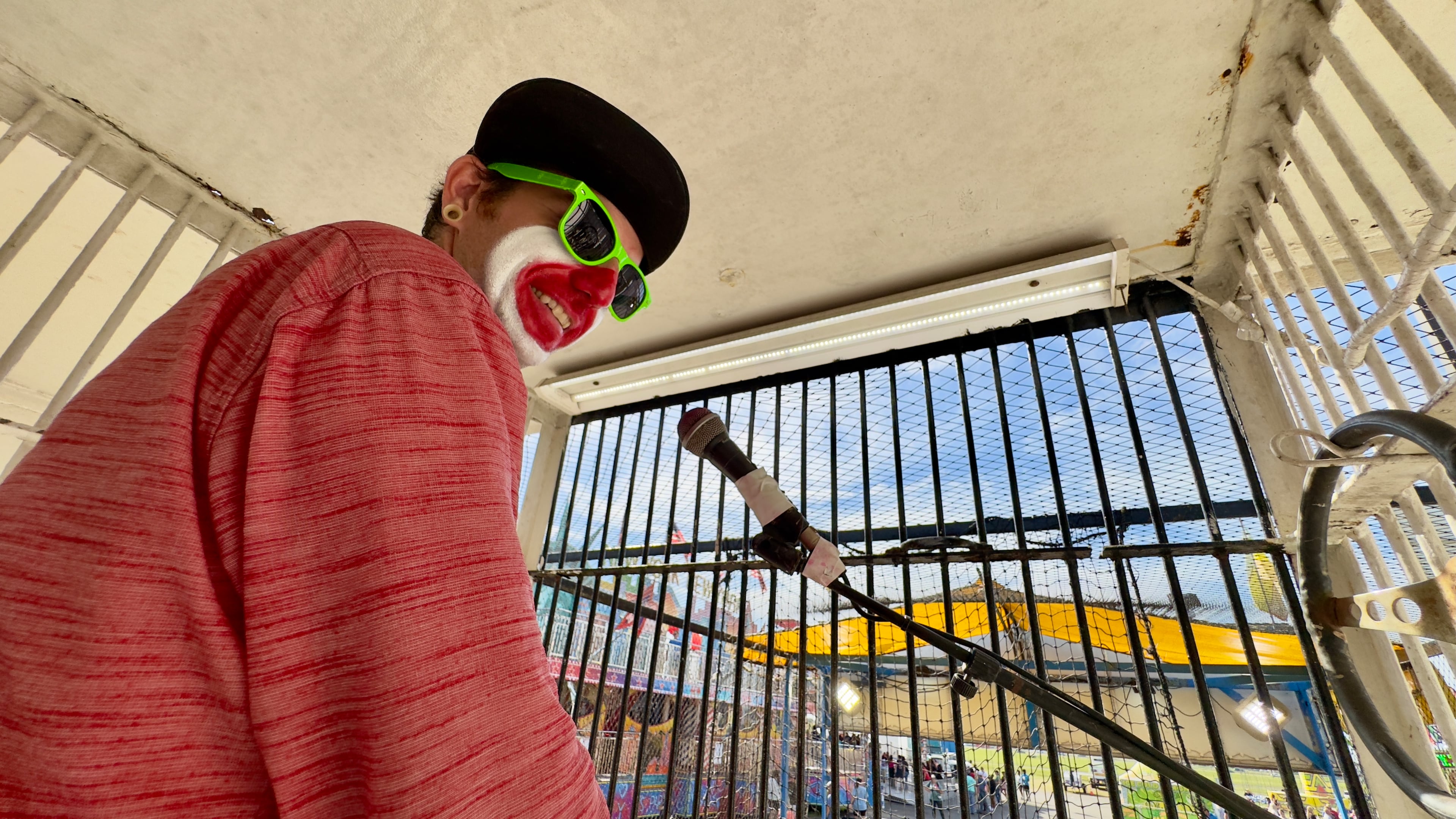 In his cage overlooking the midway, Justin Smith, a dunking-booth clown at the Georgia National Fair, barks quips at fairgoers via loudspeakers. (Joe Kovac Jr./AJC)
