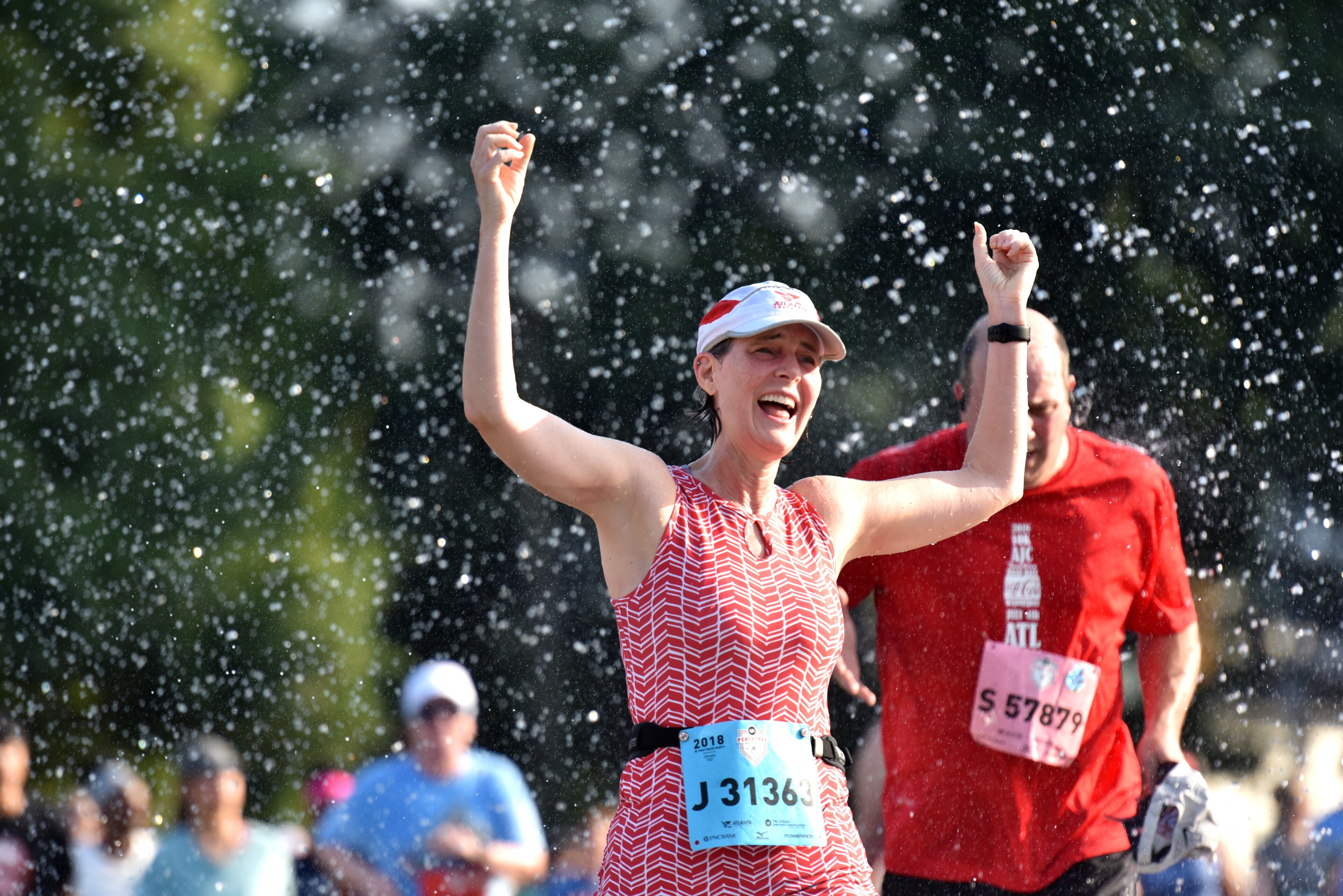 July 4, 2018 Atlanta - Runners cool off in a shower of water that refreshed them just before they approach Cardiac Hill during the AJC Peachtree Road Race on Wednesday, July 4, 2018. HYOSUB SHIN / HSHIN@AJC.COM