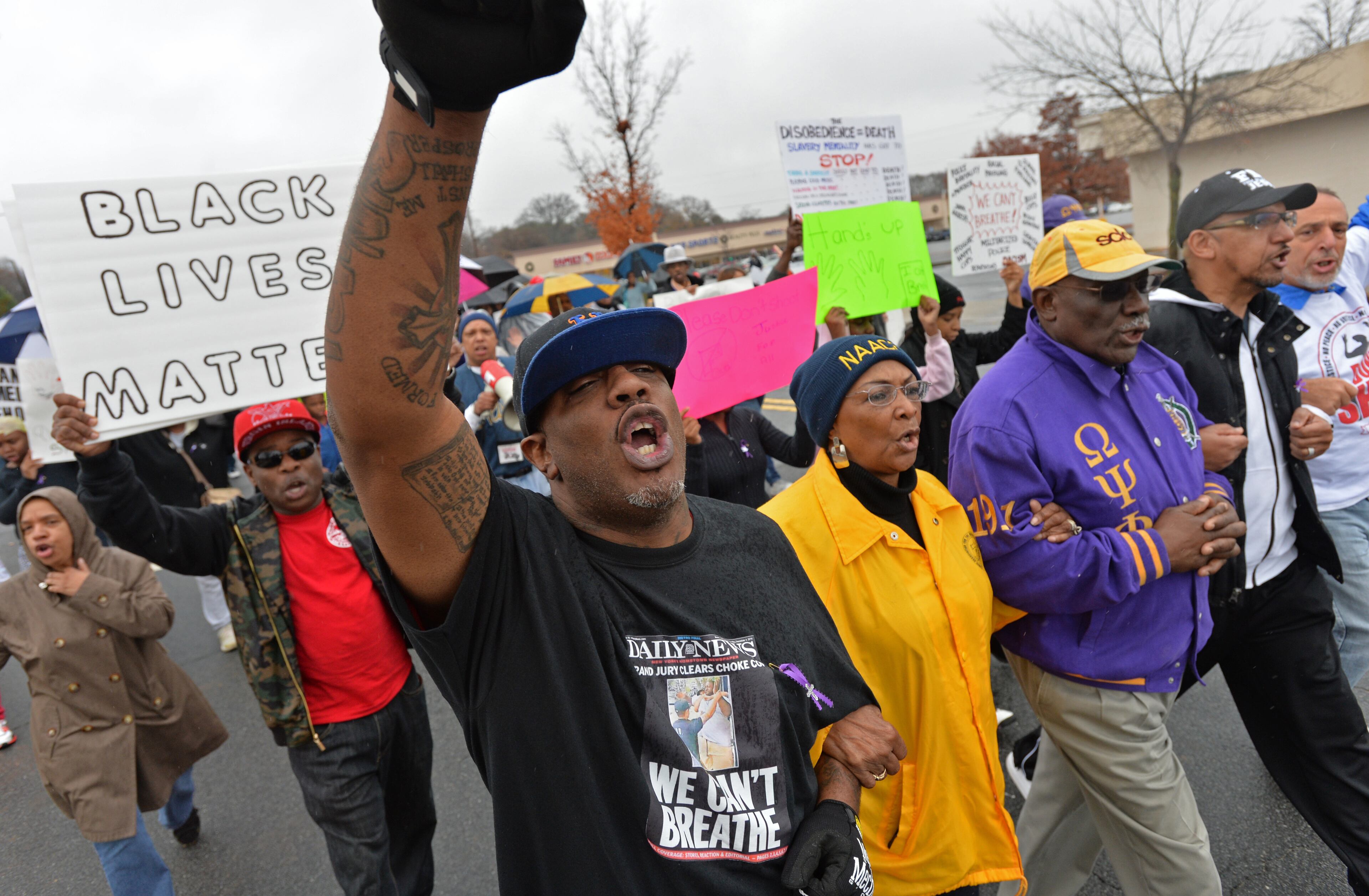 December 6, 2014 Marietta - Russell Robertson, with Occupy The Hood ATL, pumps up his fist as he marches with other protesters toward the Marietta Square during their peaceful demonstration against decisions not to indict white police officers in the deaths of unarmed black men in Ferguson, Mo., and in New York City on Saturday, December 6, 2014. HYOSUB SHIN / HSHIN@AJC.COM