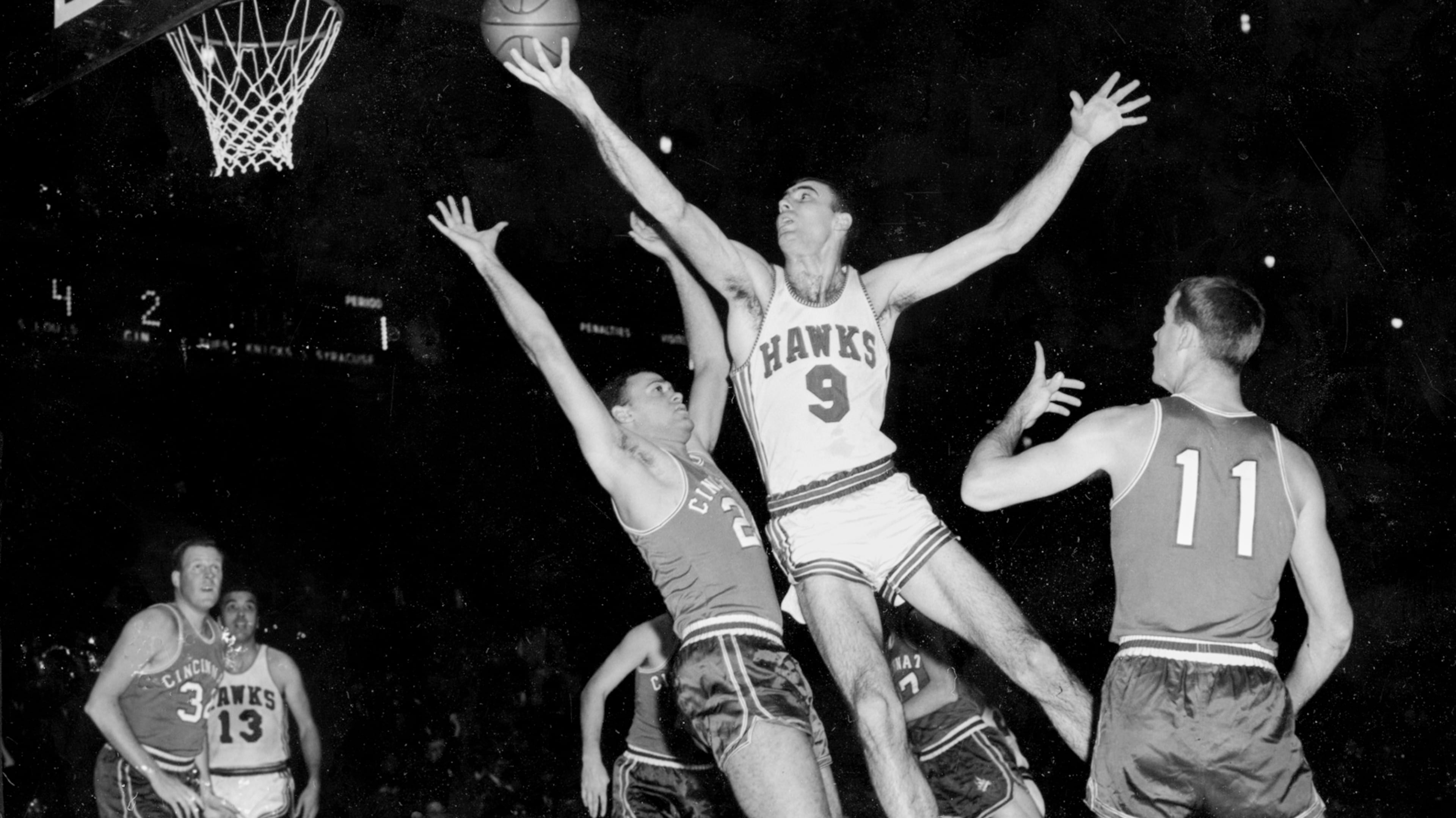 FILE - FILE - In this Dec. 10, 1957, file photo, Bob Pettit, of the St. Louis Hawks, leaps to make a one-handed shot but fails to connect for a score in the first quarter of an NBA basketball game against the Cincinnati Royals at Madison Square Garden in New York City. Blocking Pettit is Dick Ricketts (24) of the Royals as Jim Paxson (11) watches play. (AP Photo/File)