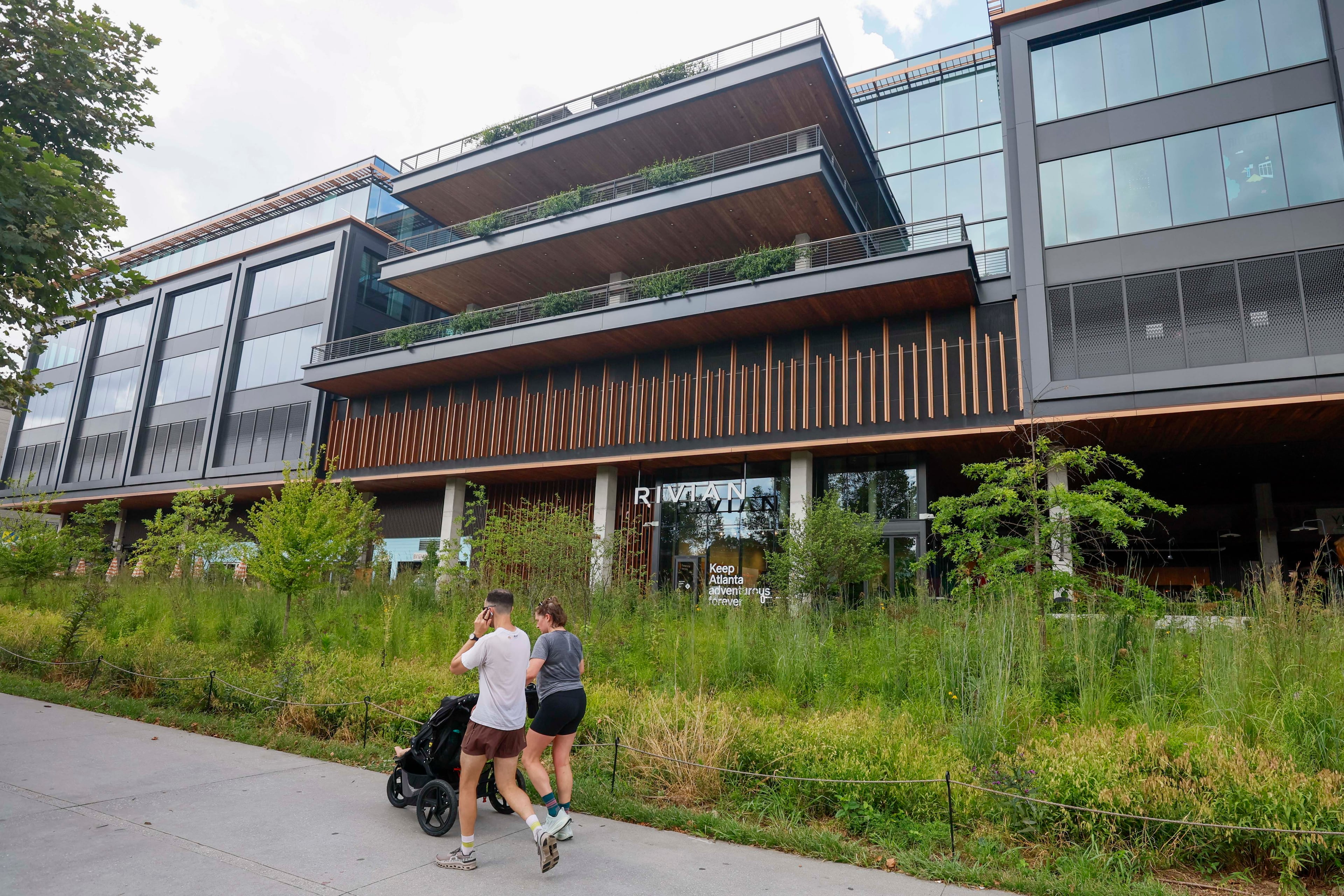 People on the beltline walk past Rivian's new East Coast headquarters in Atlanta on Tuesday, August 4, 2026. (Miguel Martinez/AJC)
