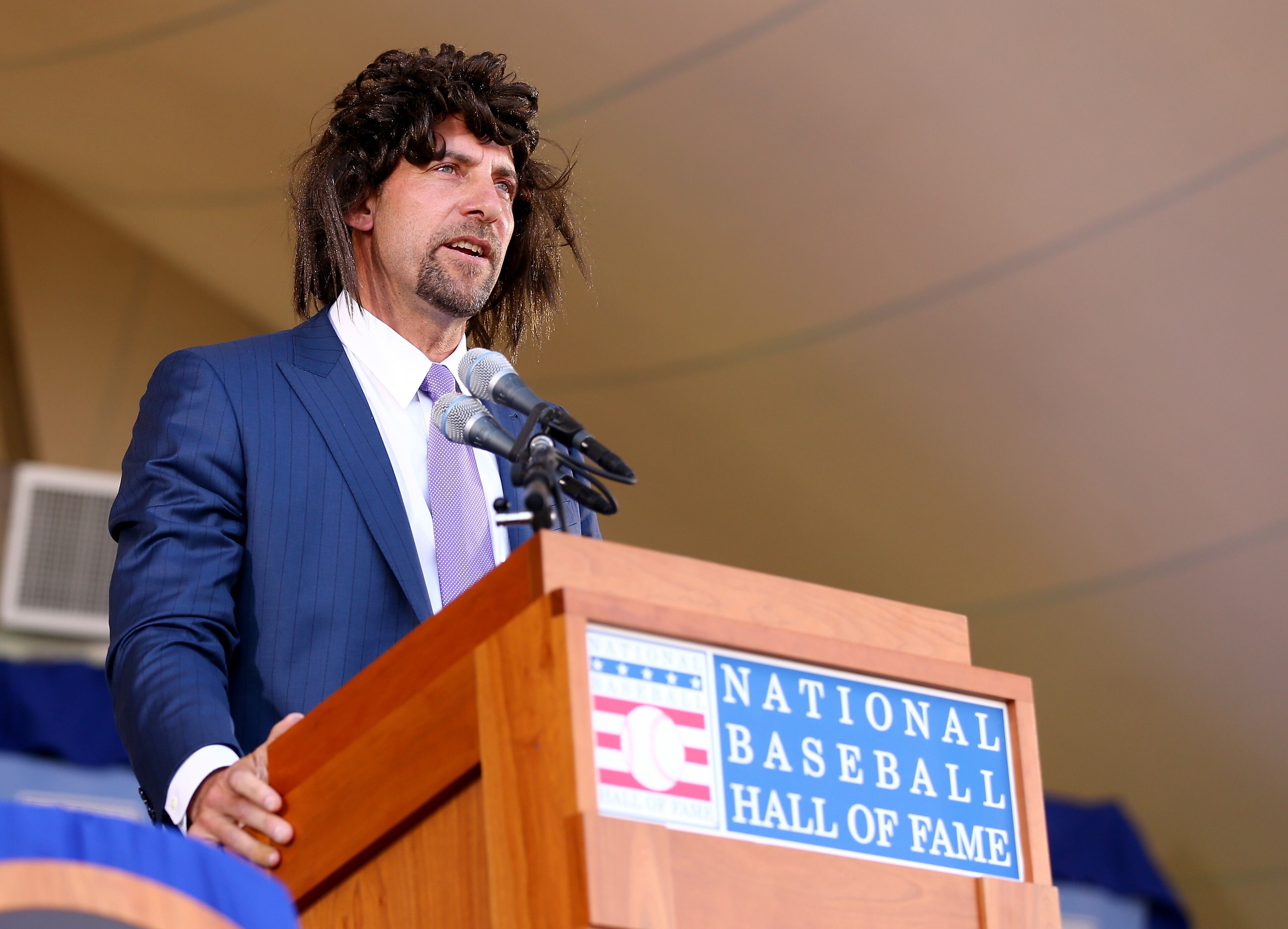 COOPERSTOWN, NY - JULY 26: John Smoltz tries to relive his early days with hair as he speaks wearing a wig during the Hall of Fame Induction Ceremony at National Baseball Hall of Fame on July 26, 2015 in Cooperstown, New York.Johnson was inducted with Pedro Martinez,Craig Biggio and John Smoltz (Photo by Elsa/Getty Images)