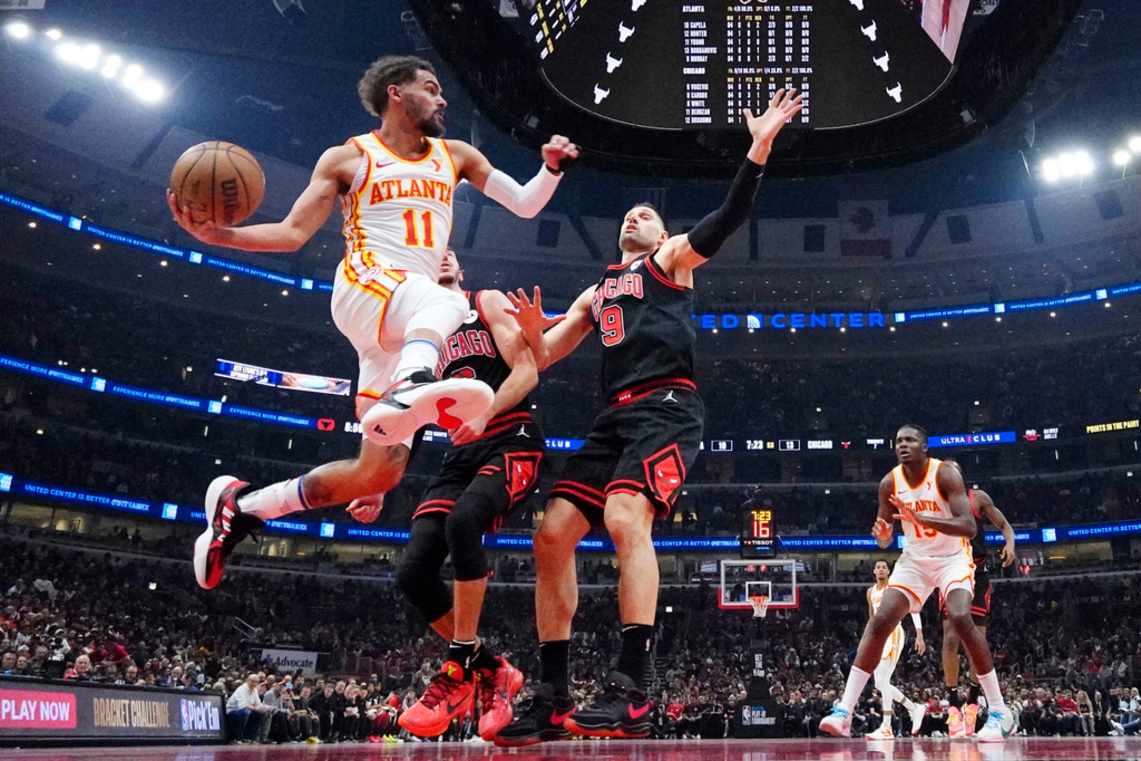 Atlanta Hawks guard Trae Young, left, looks to pass against Chicago Bulls guard Alex Caruso and center Nikola Vucevic, right, during the first half of an NBA basketball play-in tournament game in Chicago, Wednesday, April 17, 2024. Chicago won 131-116. (AP Photo/Nam Y. Huh)