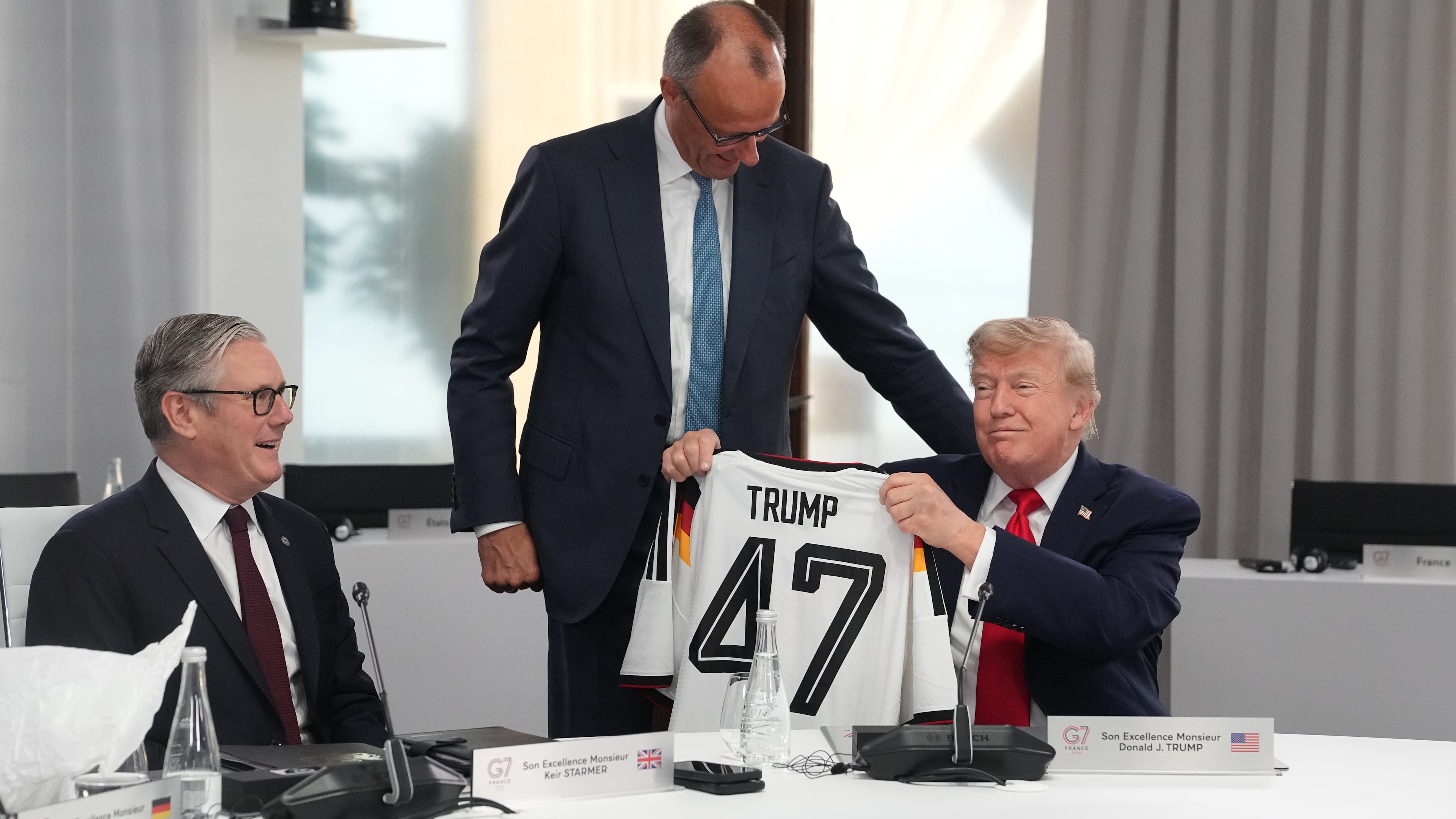 U.S. President Donald Trump, right, holds up a jersey with the number 47 on it as British Prime Minister Keir Starmer, left, and German Chancellor Friedrich Merz look on during a working session at the G7 summit in Evian-les-Bains, France, Tuesday, June 16, 2026. (AP Photo/Thibault Camus, Pool)