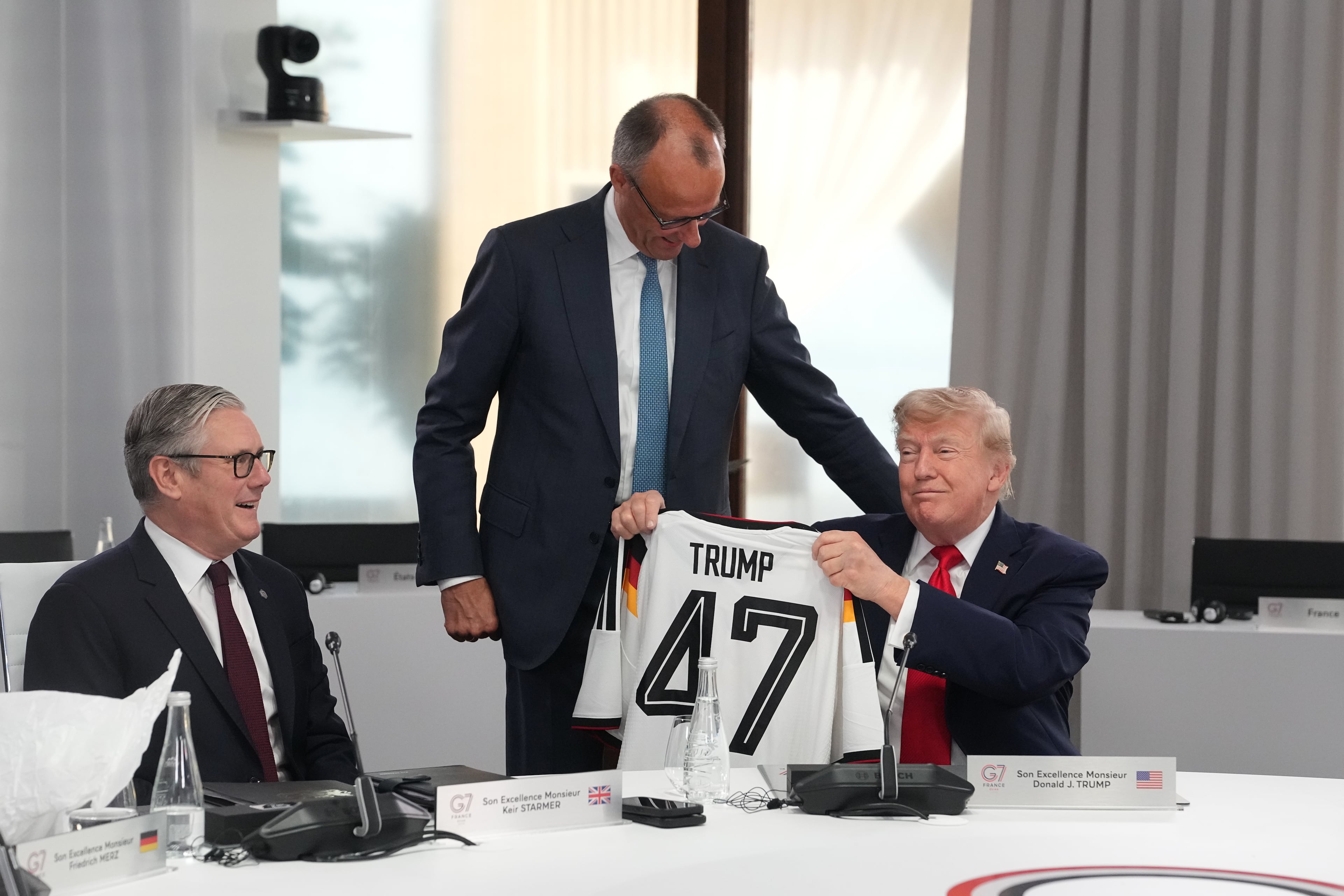 President Donald Trump (right) holds up a jersey with the number 47 on it as British Prime Minister Keir Starmer (left) and German Chancellor Friedrich Merz look on during a working session at the G7 summit in Evian-les-Bains, France, on Tuesday. (Thibault Camus/AP)