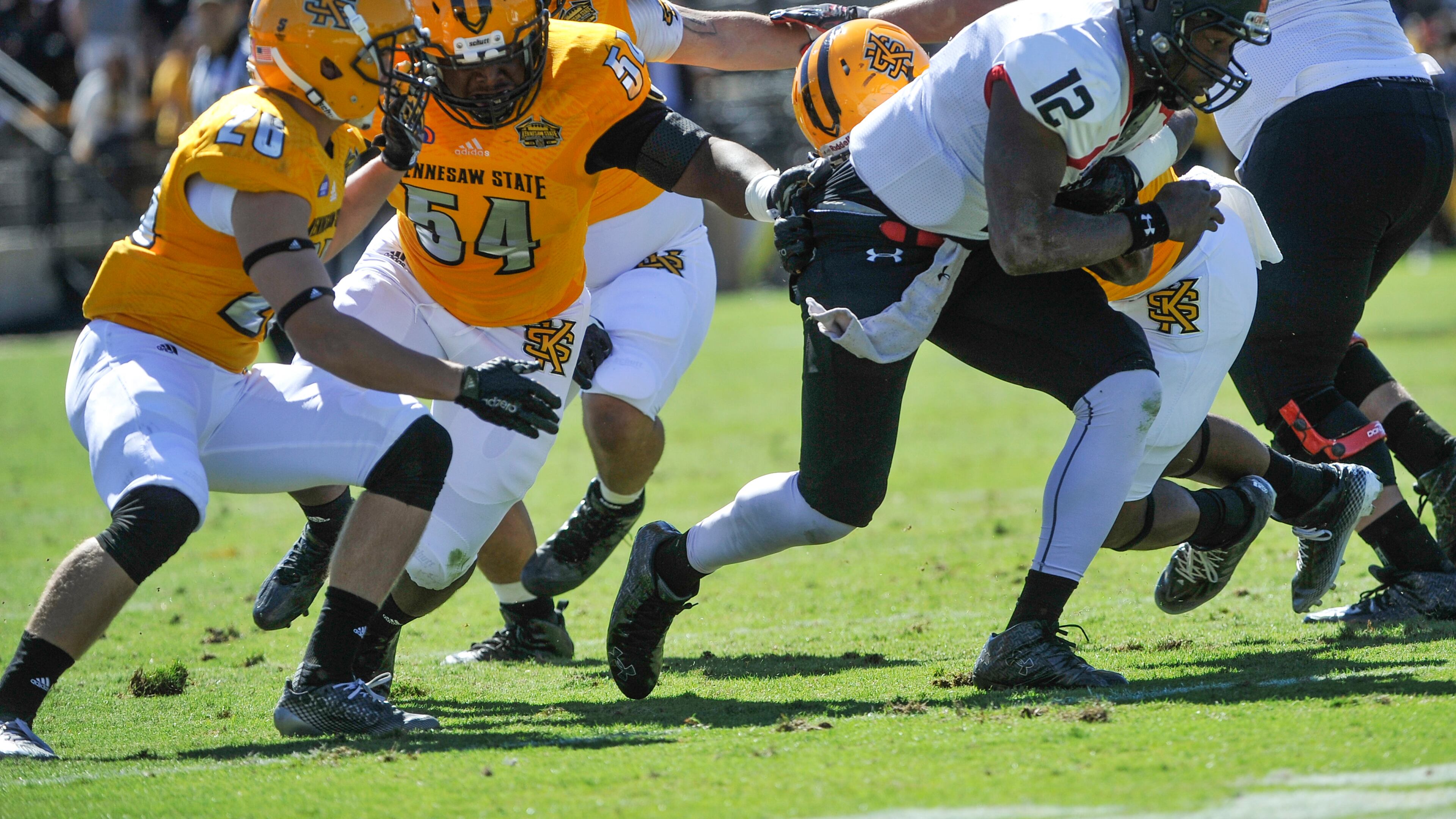 Kennesaw State linebacker Kyron Minter (54) tries to hold on to Gardner-Webb quarterback Tyrell Maxwell (12) as defensive back Taylor Henkle (26) also defends during the first half of an NCAA college football game, Saturday, Oct. 17, 2015, in Kennesaw, Ga. (Photo/John Amis)