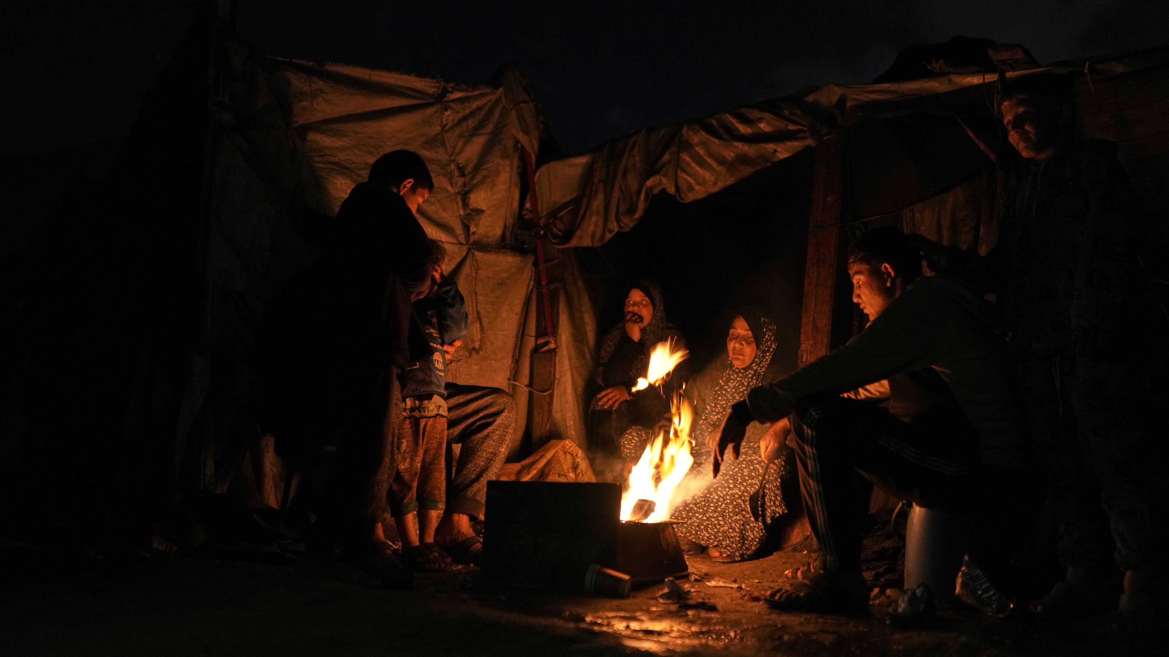 Displaced Palestinians warm themselves around a fire at a tent camp in Gaza City, Sunday, Jan. 18, 2026. (AP Photo/Jehad Alshrafi)