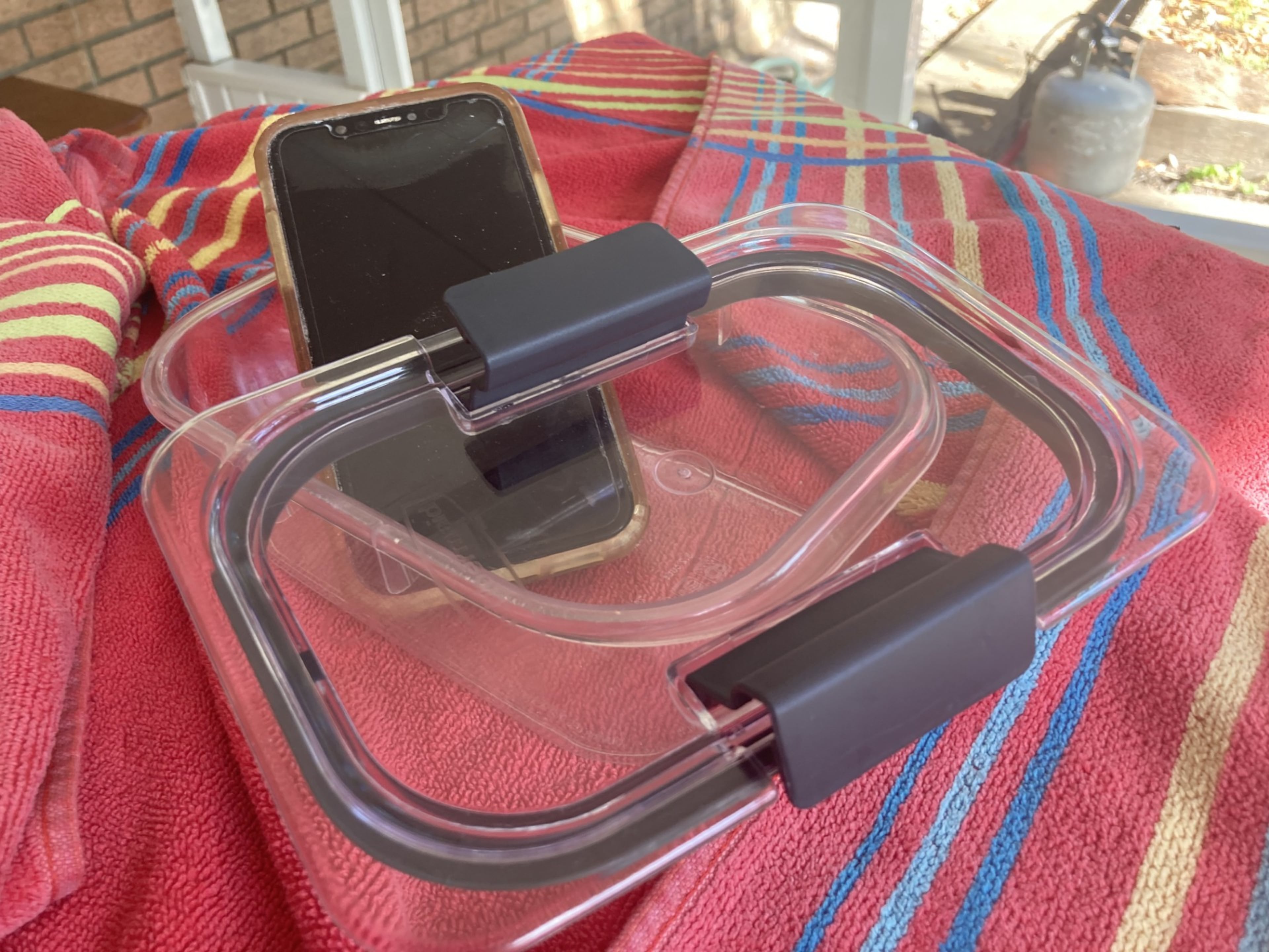 This Tupperware-encased cellphone was lost while its owner paddleboarded off the beach of Tybee Island in August 2025. The device was recovered on another beach 20 miles away in March. (Adam Van Brimmer/AJC)