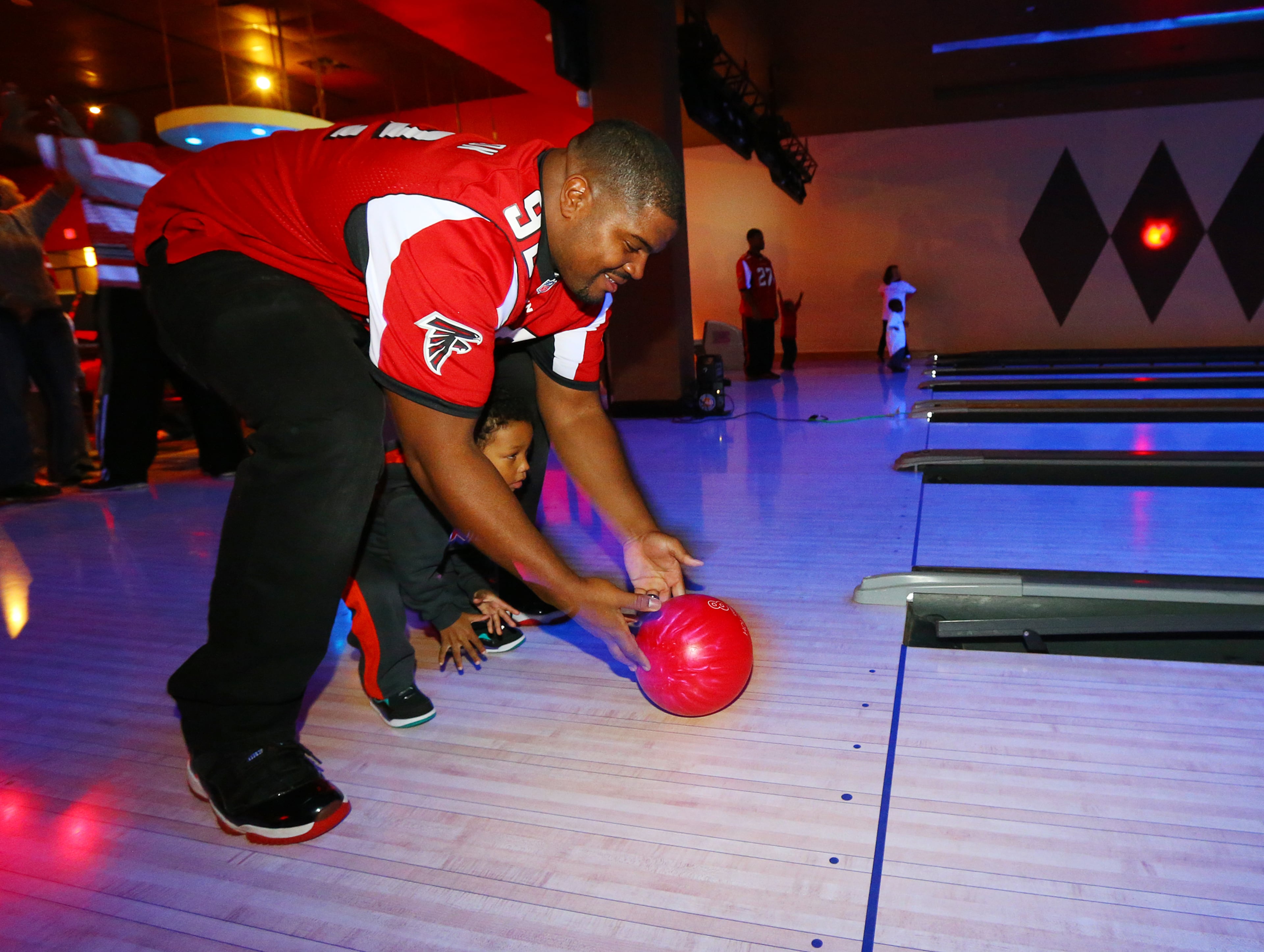 Atlanta Falcons defensive tackle Travian Robertson helps Salif Kagni, 3, bowl while Falcons players and UnitedHealthcare of Georgia treat children from the Make-A-Wish Foundation and their families to a night of bowling at Dave & Busters on Tuesday, Dec. 17, 2013.
