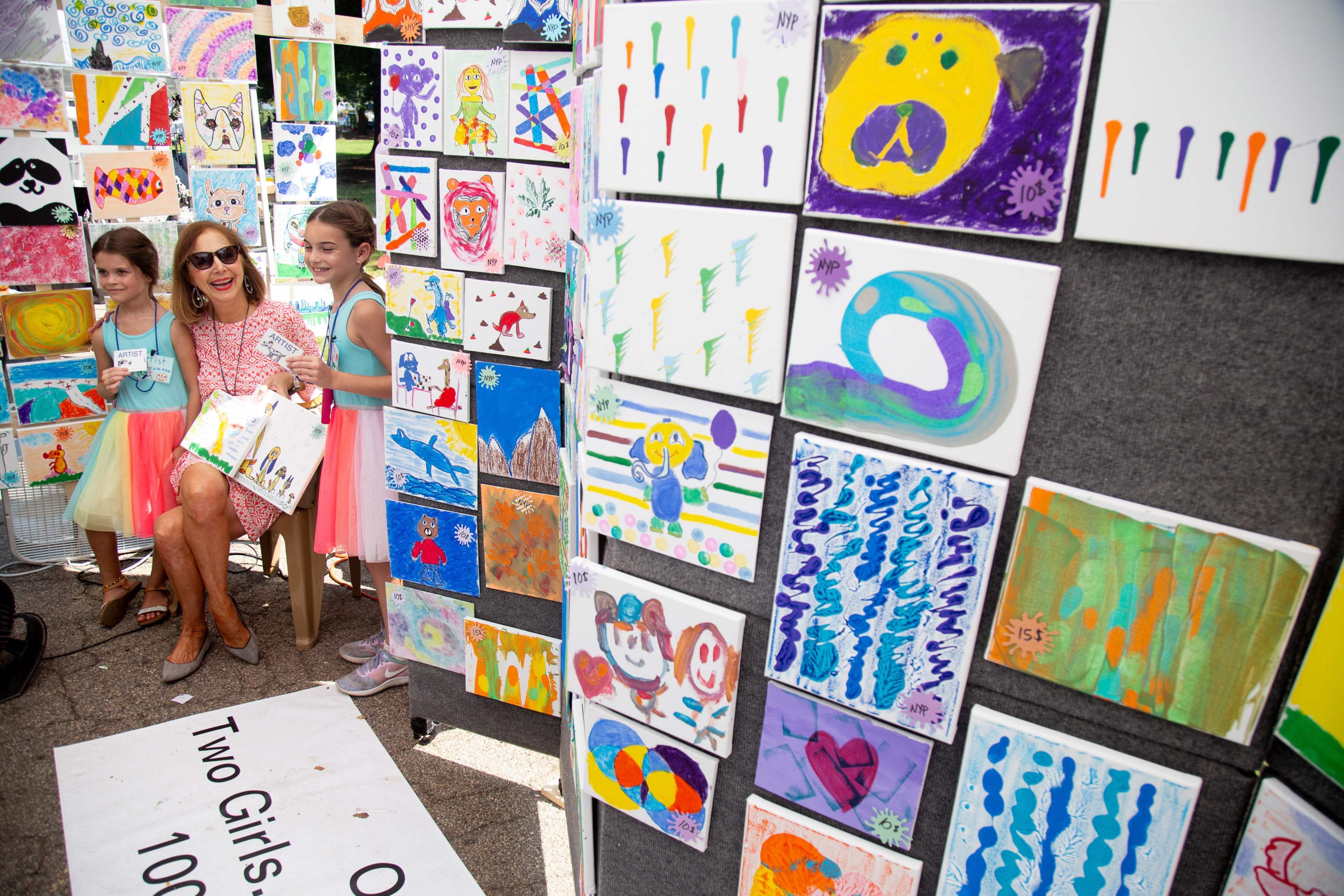 Sisters Stevanna (L) and Milana Snowdy pose for a photograph with a patron that bought one of their paintings during the Piedmont Park Summer Arts Festival in Atlanta on Sunday, August 18, 2019. The sisters painted over 500 canvases to raise money for cancer research. STEVE SCHAEFER / SPECIAL TO THE AJC