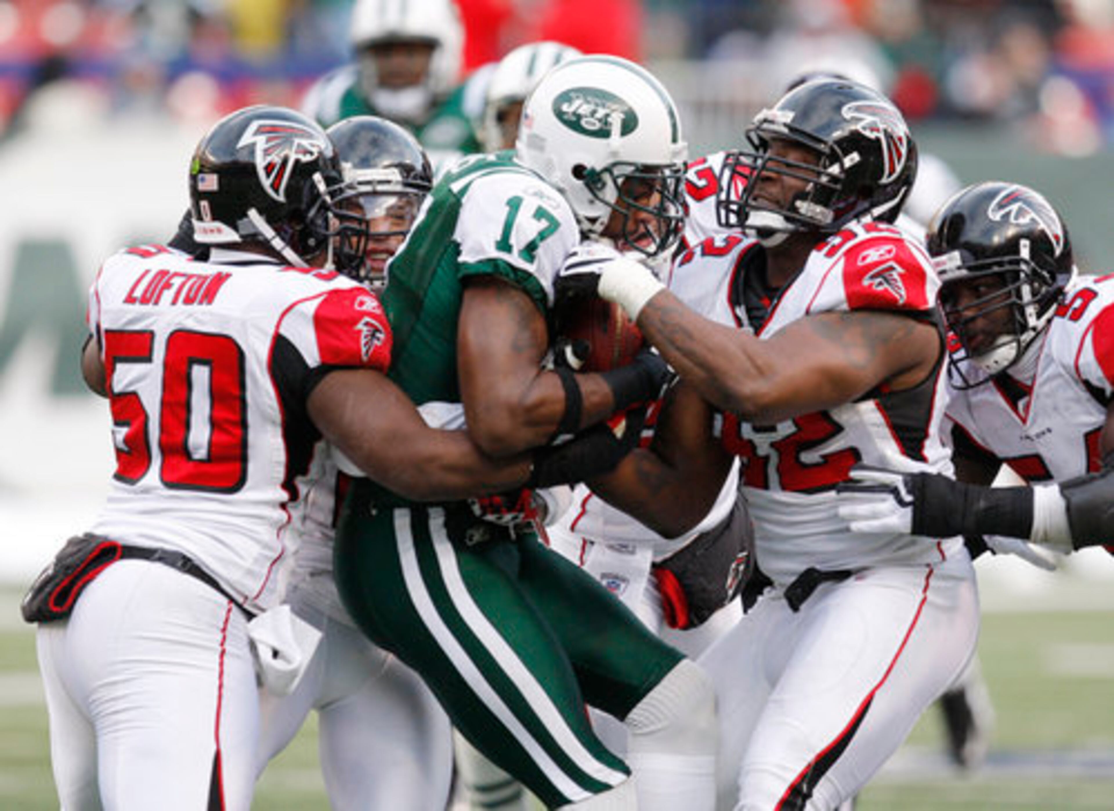 Falcons' Stephen Nicholas (right), Chauncey Davis and Curtis Lofton (50) attempt to tackle New York Jets' wideout Braylon Edwards.