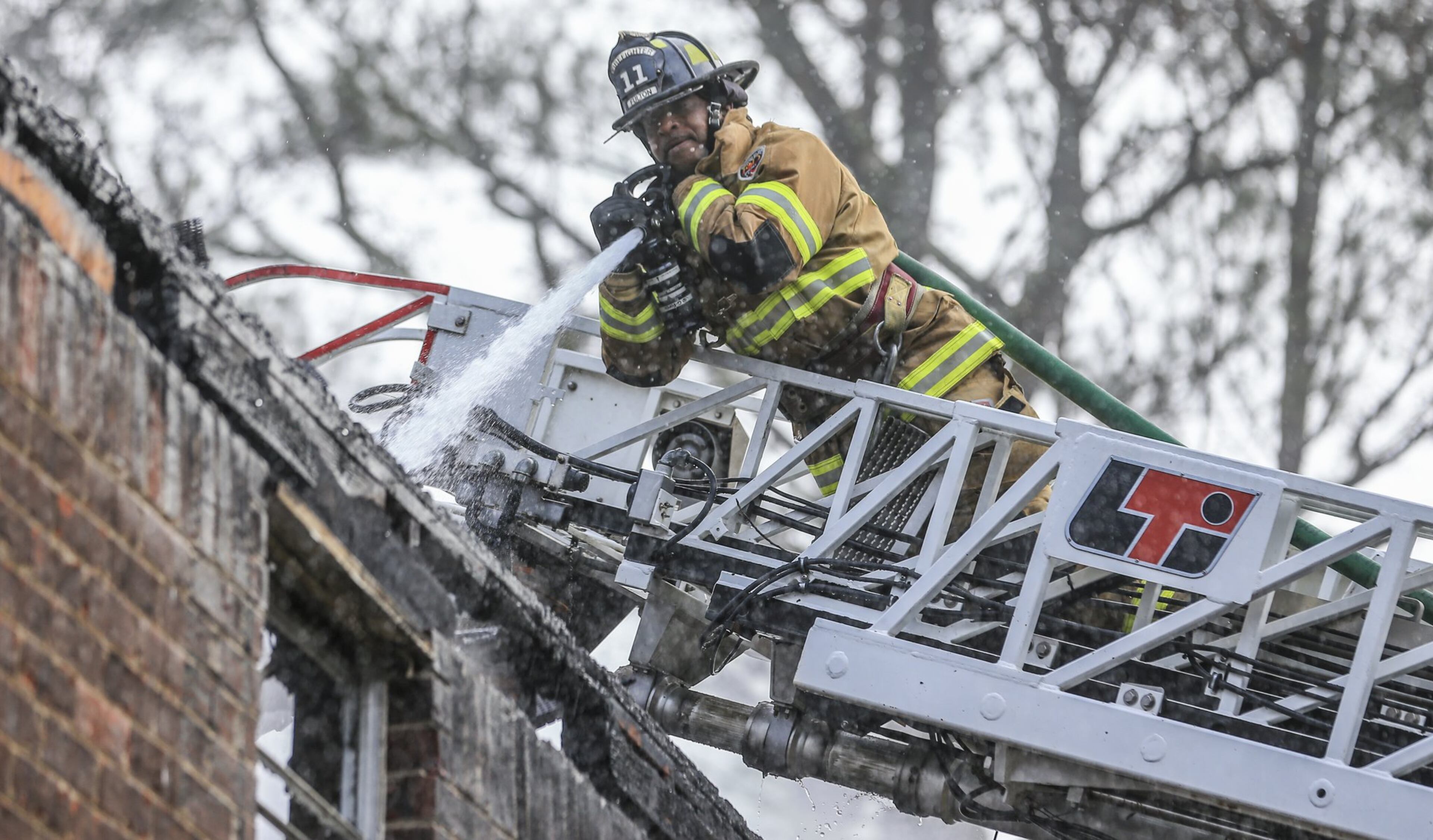 Fulton County firefighter John Henderson hits hot spots during an apartment fire. The Fulton County fire department transitioned to the city of South Fulton Monday. JOHN SPINK/JSPINK@AJC.COM AJC FILE PHOTO