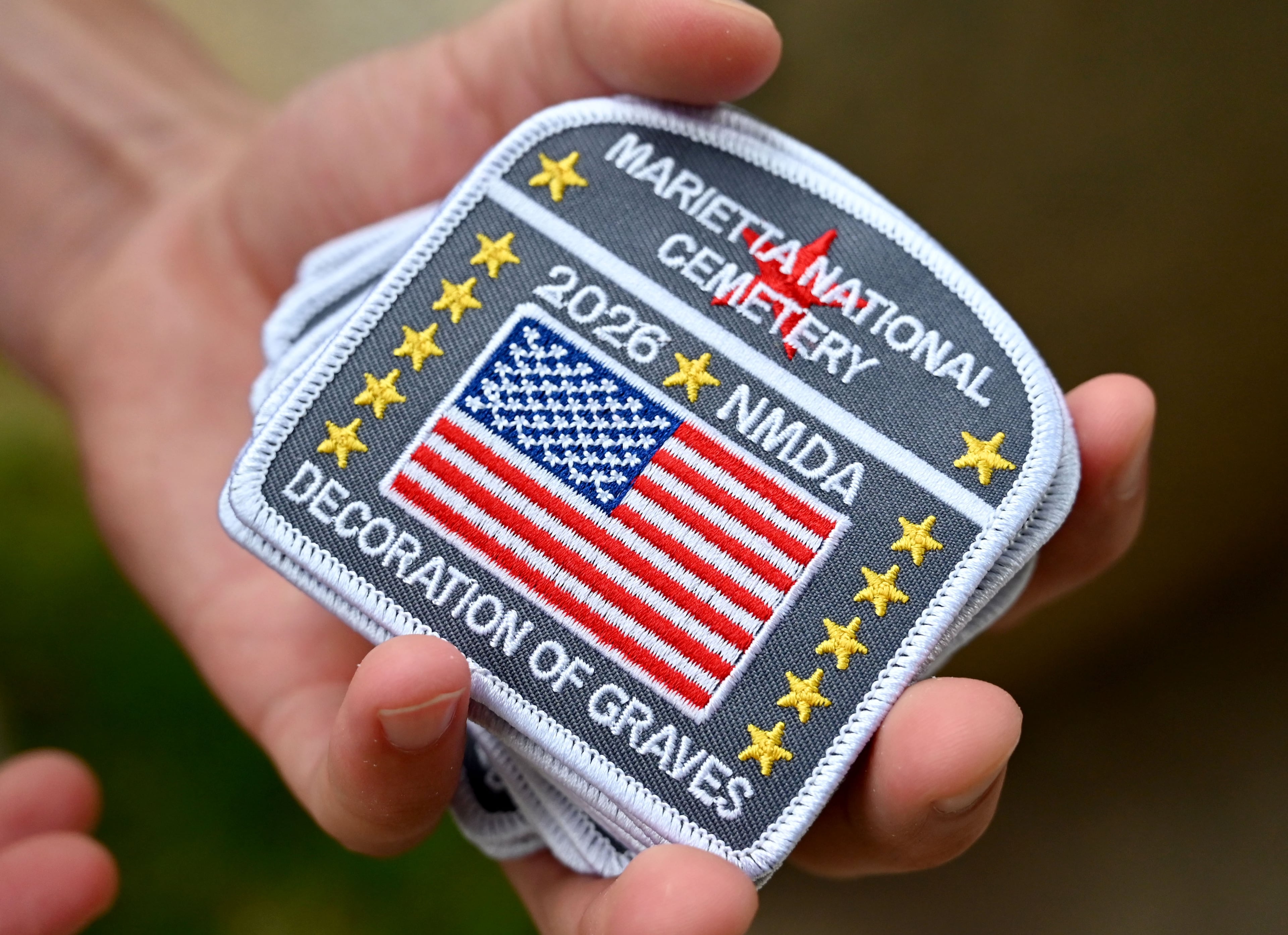 Each Scout receives a commemorative patch upon arrival at Marietta National Cemetery on Saturday, May 23, 2026, in Marietta. Scouting groups in the community place more than 18,000 U.S. veteran grave flags at Marietta National Cemetery each year on the Saturday before Memorial Day, helping prepare for Monday’s ceremony. The long-running service project—organized with the National Memorial Day Association of Georgia—also gives youth and adults an opportunity to honor fallen service members and learn about their sacrifices and the area’s history. (Hyosub Shin/AJC)