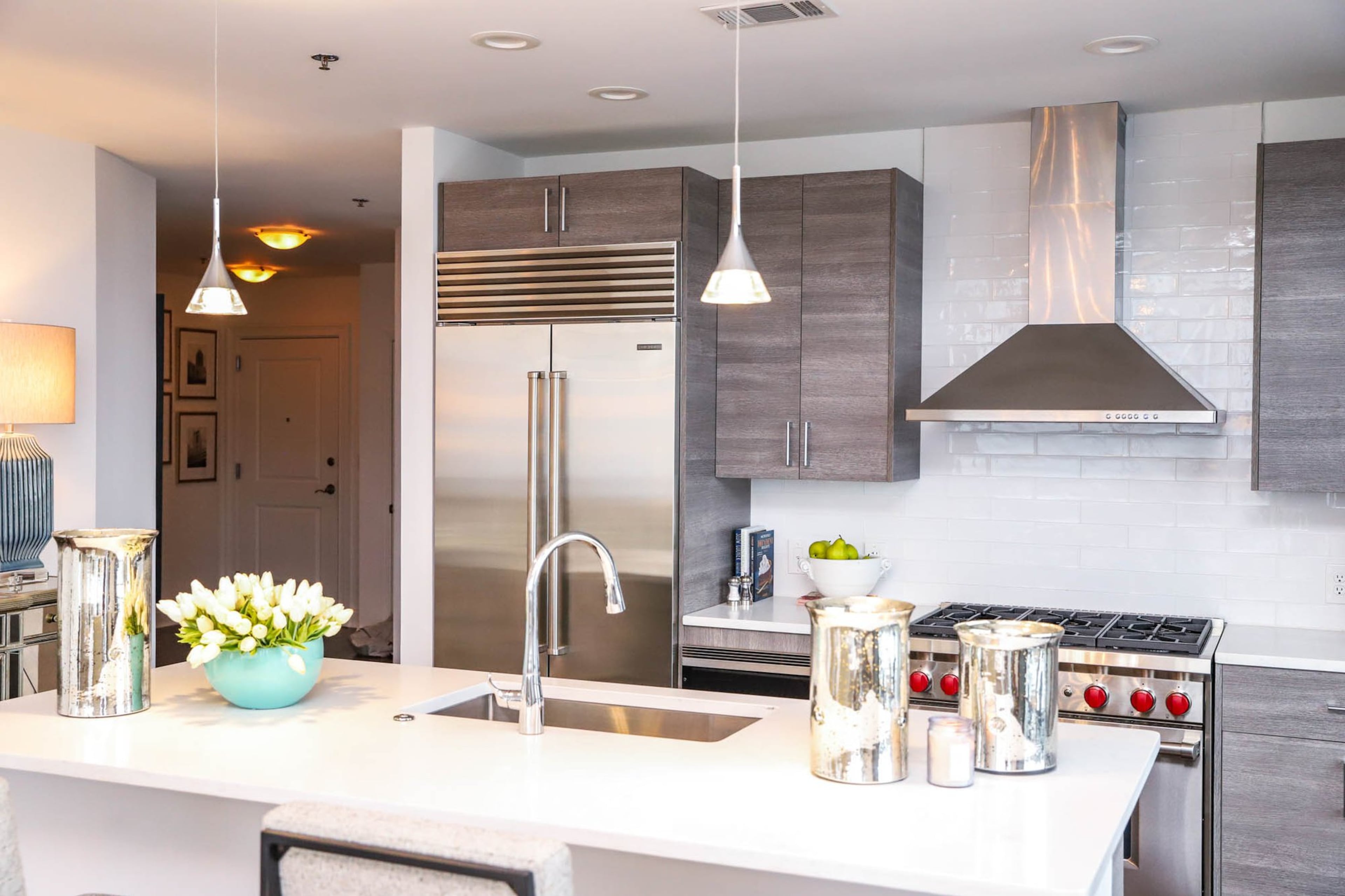 On the counter in the kitchen is one of Jeannie Waldman’s favorite accent pieces in her home, a Nico Large Bowl in aqua by Cyan Design filled with faux tulips that add a touch of freshness to the space. The contemporary kitchen is bright and industrial with subtle accents like the tulips, the mercury glass candle holders and the sparkling pendant lights to add hints of warmth. Text by Shannon Dominy. Photo by Reynolds Rogers.