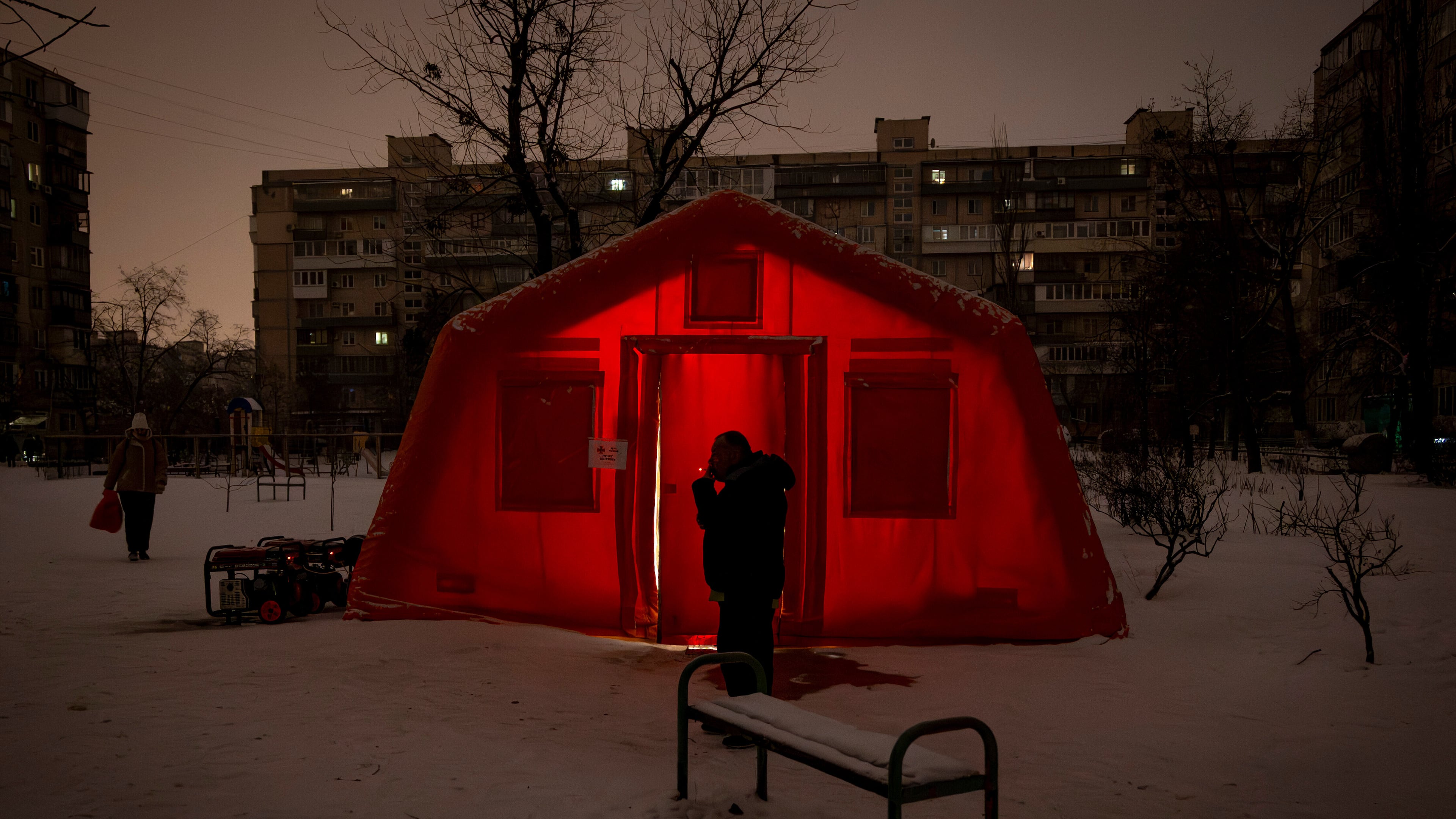 A man smokes outside of an emergency tent where people can warm up following Russia's regular air attacks against the country's energy objects, that leave residents without power, water and heating in the dead of winter, in Kyiv, Ukraine, Tuesday, Jan. 13, 2026. (AP Photo/Danyil Bashakov)
