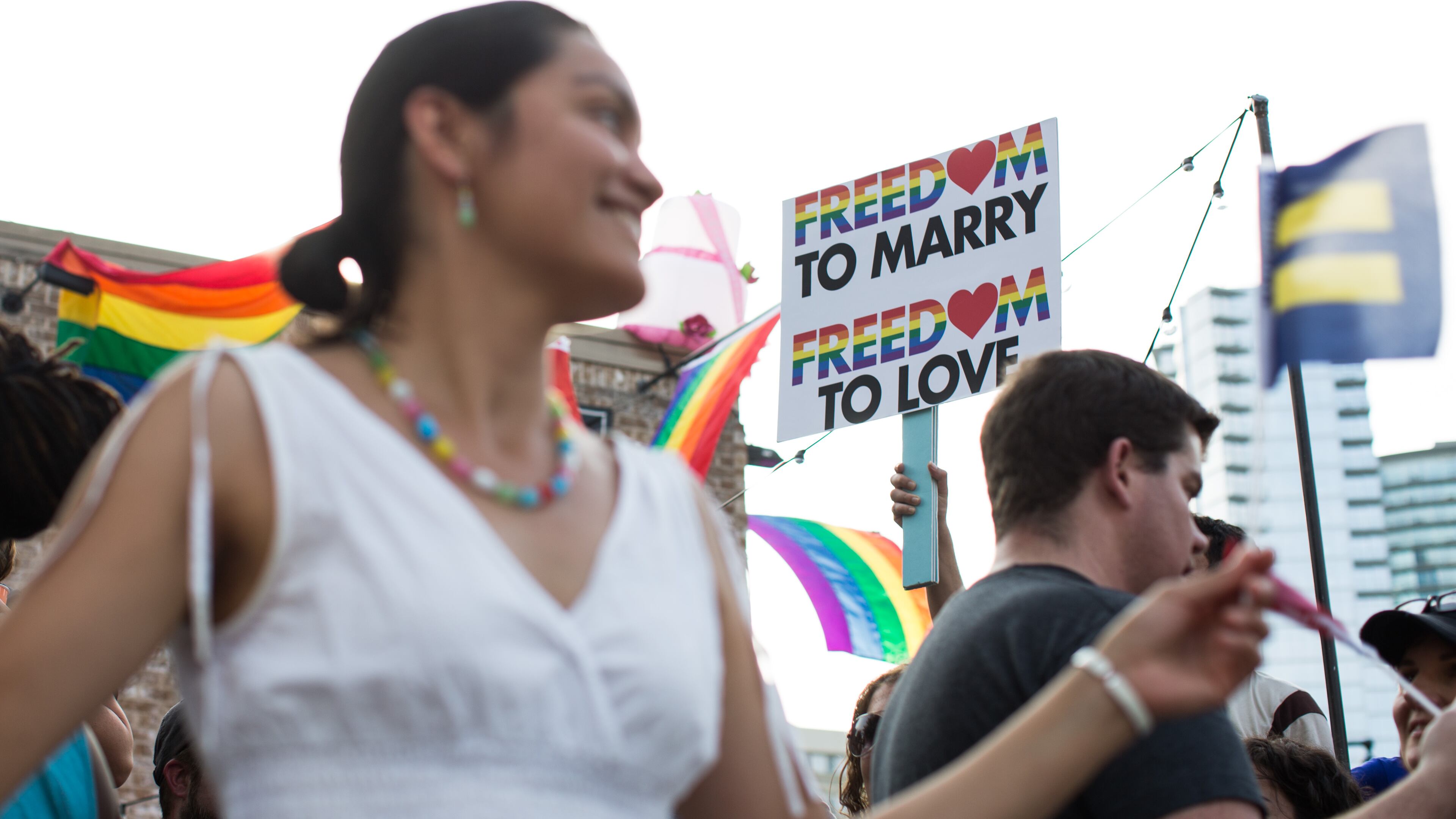 Laila Flores, left, celebrates as Chip O' Kelly, partially seen, holds a sign in downtown Atlanta following the Supreme Court's ruling that made gay marriage constitutional across the nation, Friday, June 26, 2015. (BRANDEN CAMP/AJC FILE PHOTO)