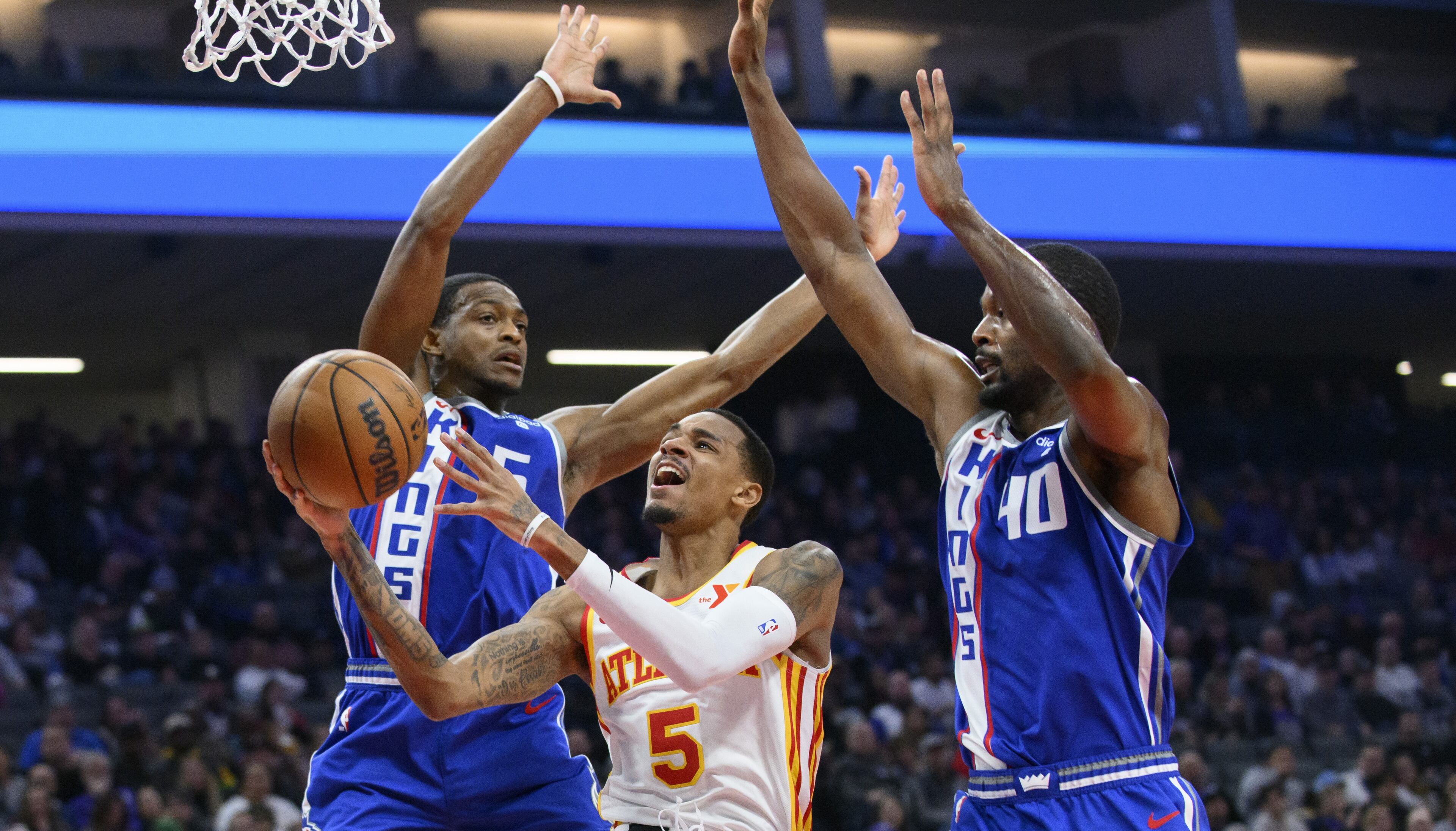 Hawks guard Dejounte Murray goes up for a shot against Kings guard De'Aaron Fox (left) and forward Harrison Barnes (40) during the first half of Monday's Hawks-Kings game in Sacramento.