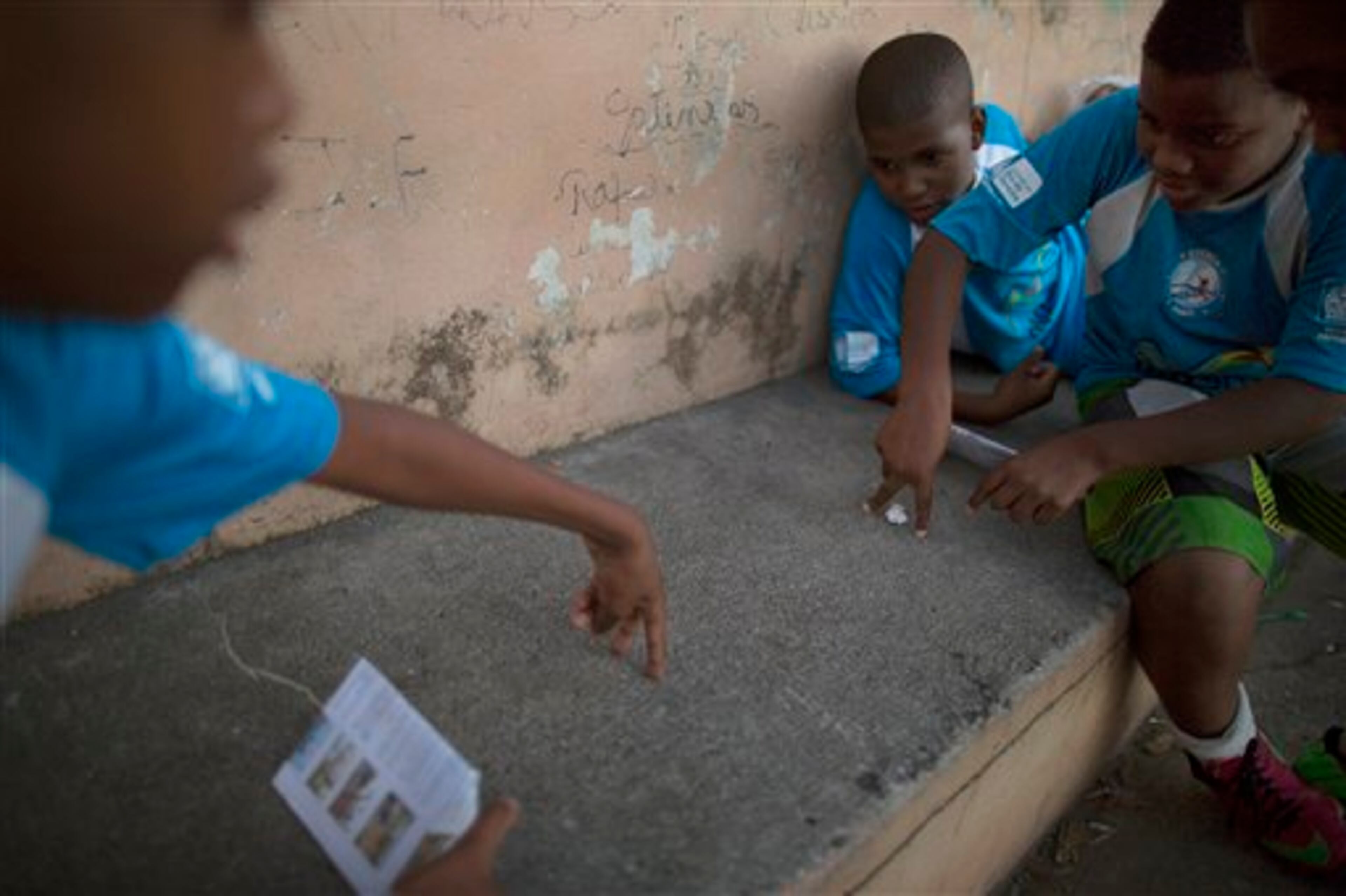 In this Wednesday, June 4, 2014 photo, kids play soccer using a paper ball and goalpost as they wait for their turn to play soccer in a court in the Mangueira slum, near Maracana stadium in Rio de Janeiro, Brazil. "Soccer can bring changes to a nation and it can even stop wars," said Washington Fortunato, the president of Mangueira's residents' association. "However, millions were spent on the renovation of the stadium, which didn't bring any benefits to our community. We still have health and education problems...and alleys full of garbage." (AP Photo/Leo Correa)