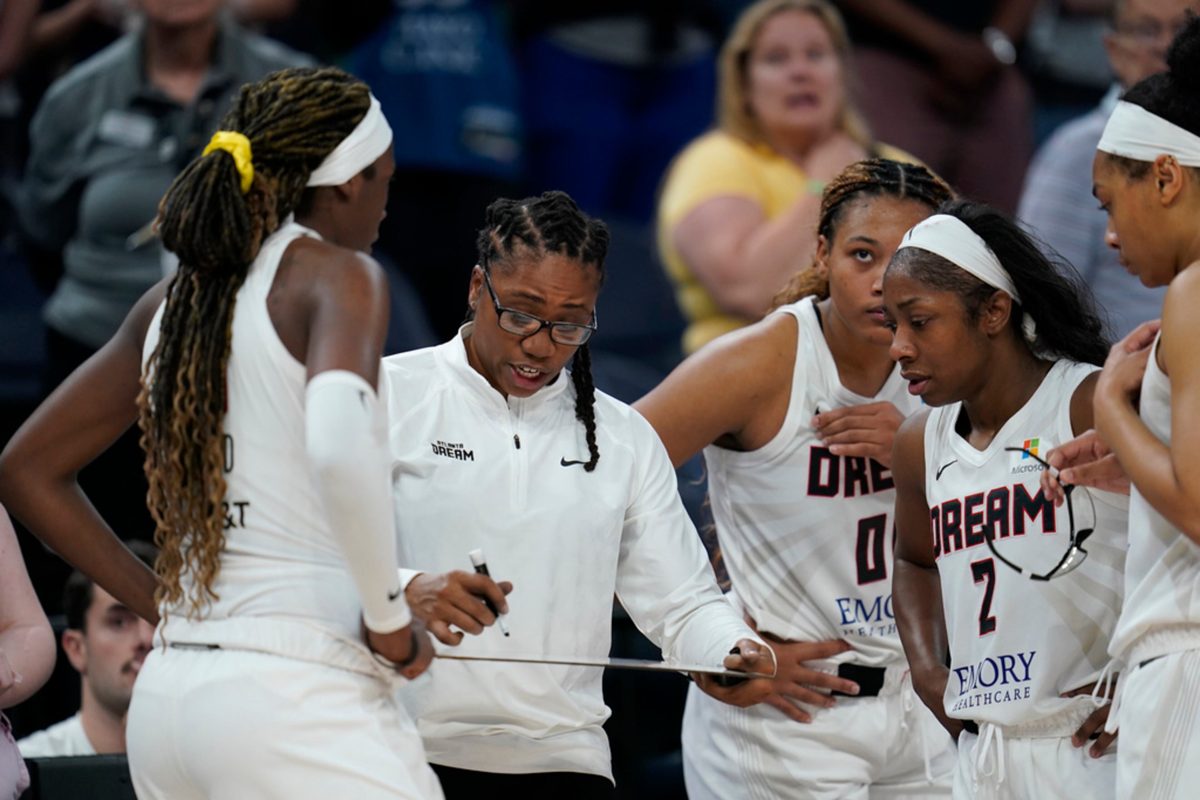 Atlanta Dream head coach Tanisha Wright, center, draws on a whiteboard during overtime of a WNBA basketball game against the Minnesota Lynx, Friday, Sept. 1, 2023, in Minneapolis. (AP Photo/Abbie Parr)