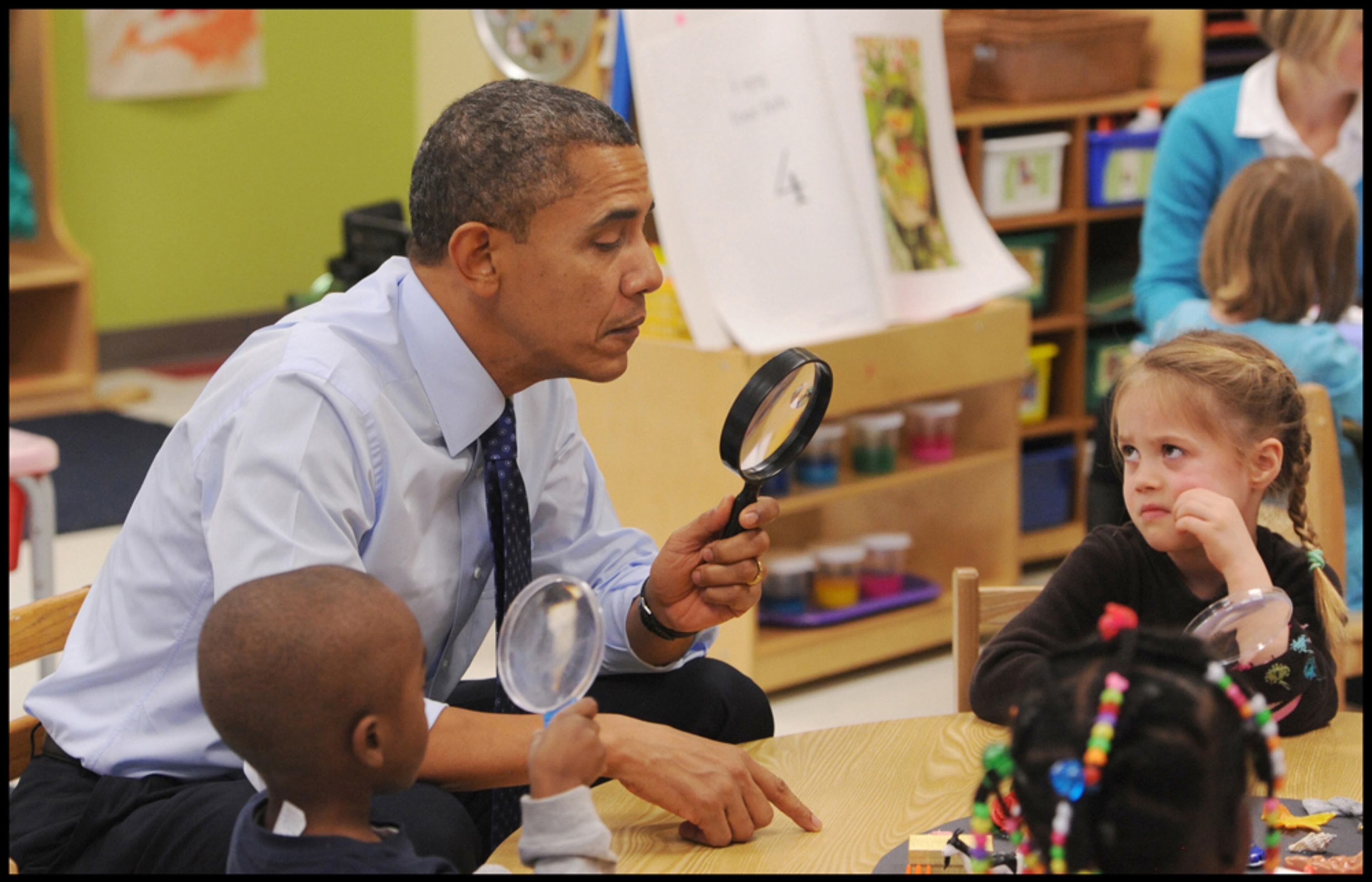 021413 Decatur: Photographing U.S. President Barack Obama inside a classroom at College Heights Early Childhood Learning Center was uneventful until he sat down at the table with this little girl. Although he was the president, he was a stranger to her and the magnifying glass made his eye appeared huge. Once she determined that he was friendly, she smiled and warmed up to him. Camera Nikon D3, Lens 70 to 200mm 2.8, ISO 2500, Aperture 4.5, Shutter speed 1/250. JOHNNY CRAWFORD / JCRAWFORD@AJC.COM