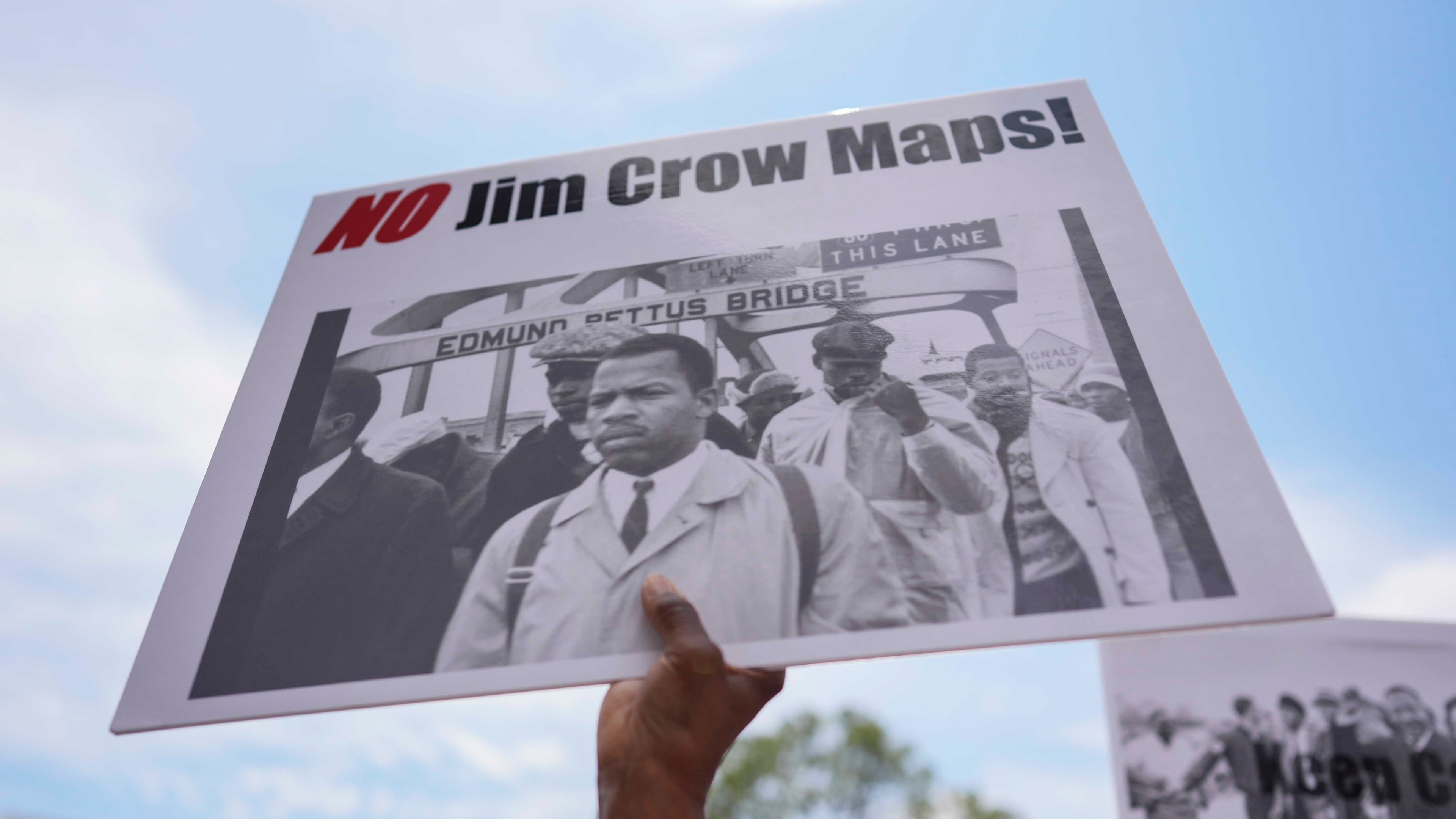 A protester holds a sign of the late Georgia Congressman John Lewis during a voting rally May 16, 2026, in Montgomery, Ala. (Mike Stewart/AP)