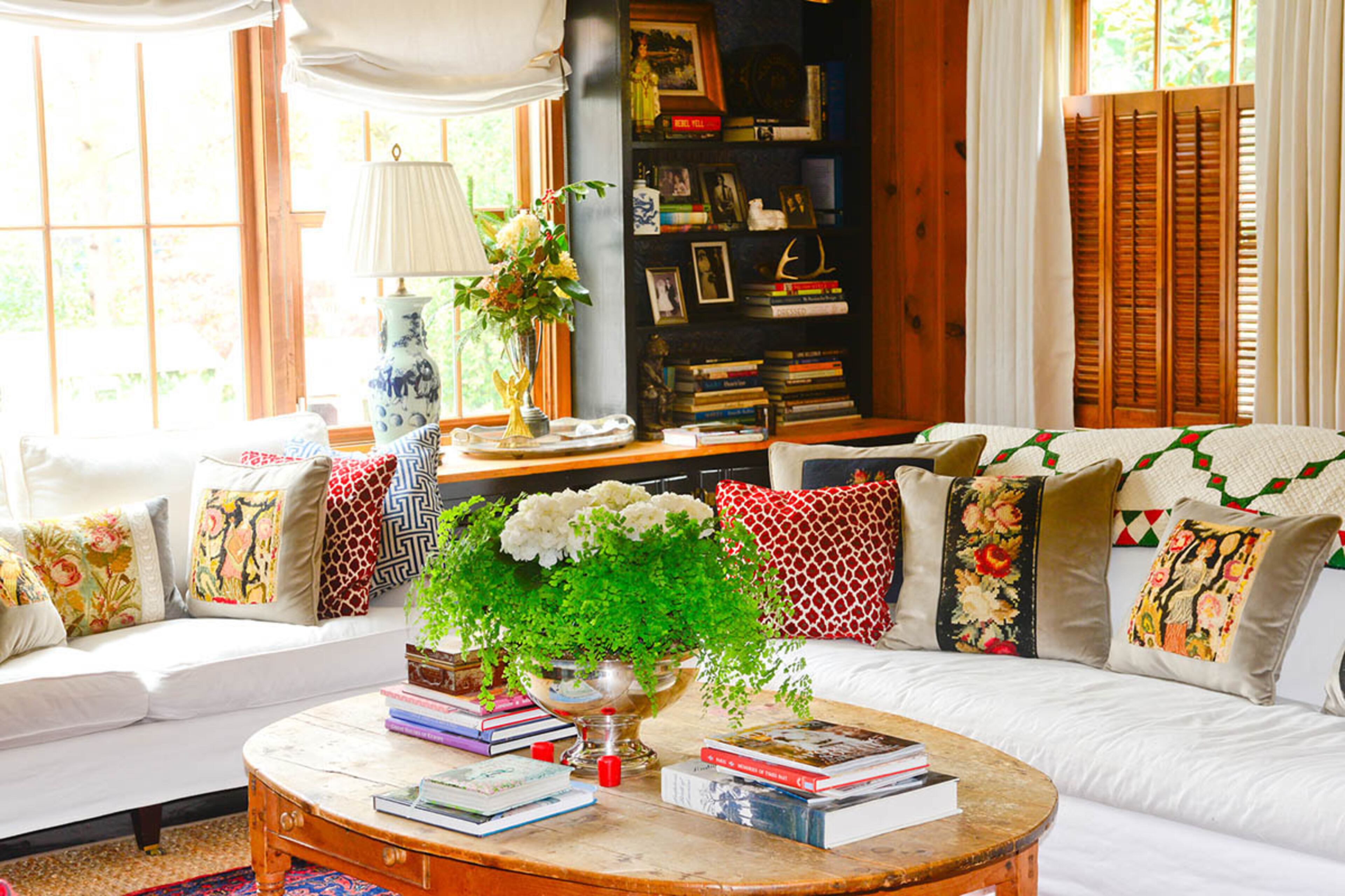 On an estate sale coffee table in the living room, an antique silver punch bowl holds an arrangement of hydrangea and baby's tear.