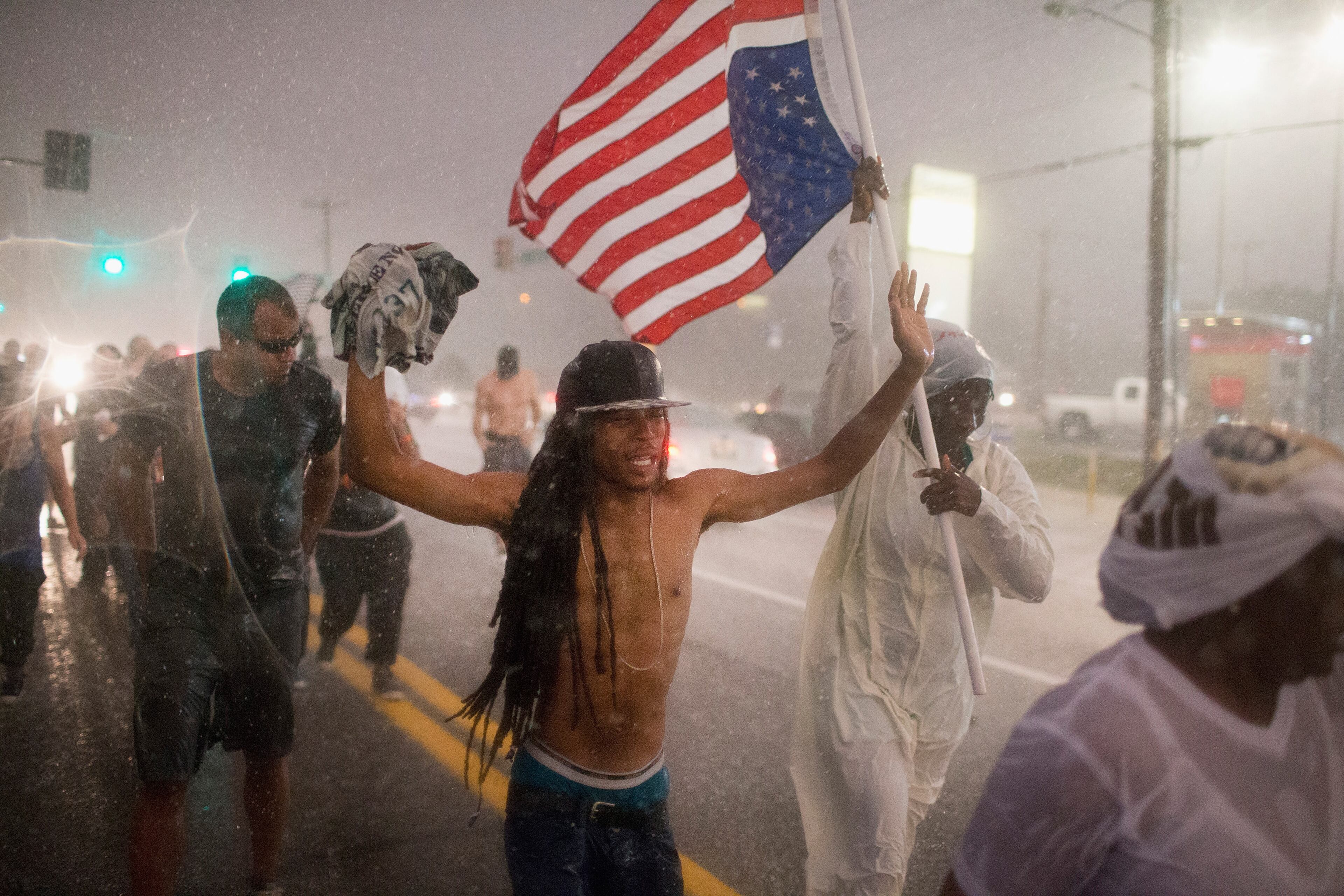 FERGUSON, MO - AUGUST 09: Demonstrators, marking the one-year anniversary of the shooting of Michael Brown, march along West Florrisant Street in a driving rain on August 9, 2015 in Ferguson, Missouri. There are reports that two people were shot when gun fire broke out during protests later in the evening. Brown was shot and killed by a Ferguson police officer on August 9, 2014. His death sparked months of sometimes violent protests in Ferguson and drew nationwide focus on police treatment of black offenders. (Photo by Scott Olson/Getty Images)