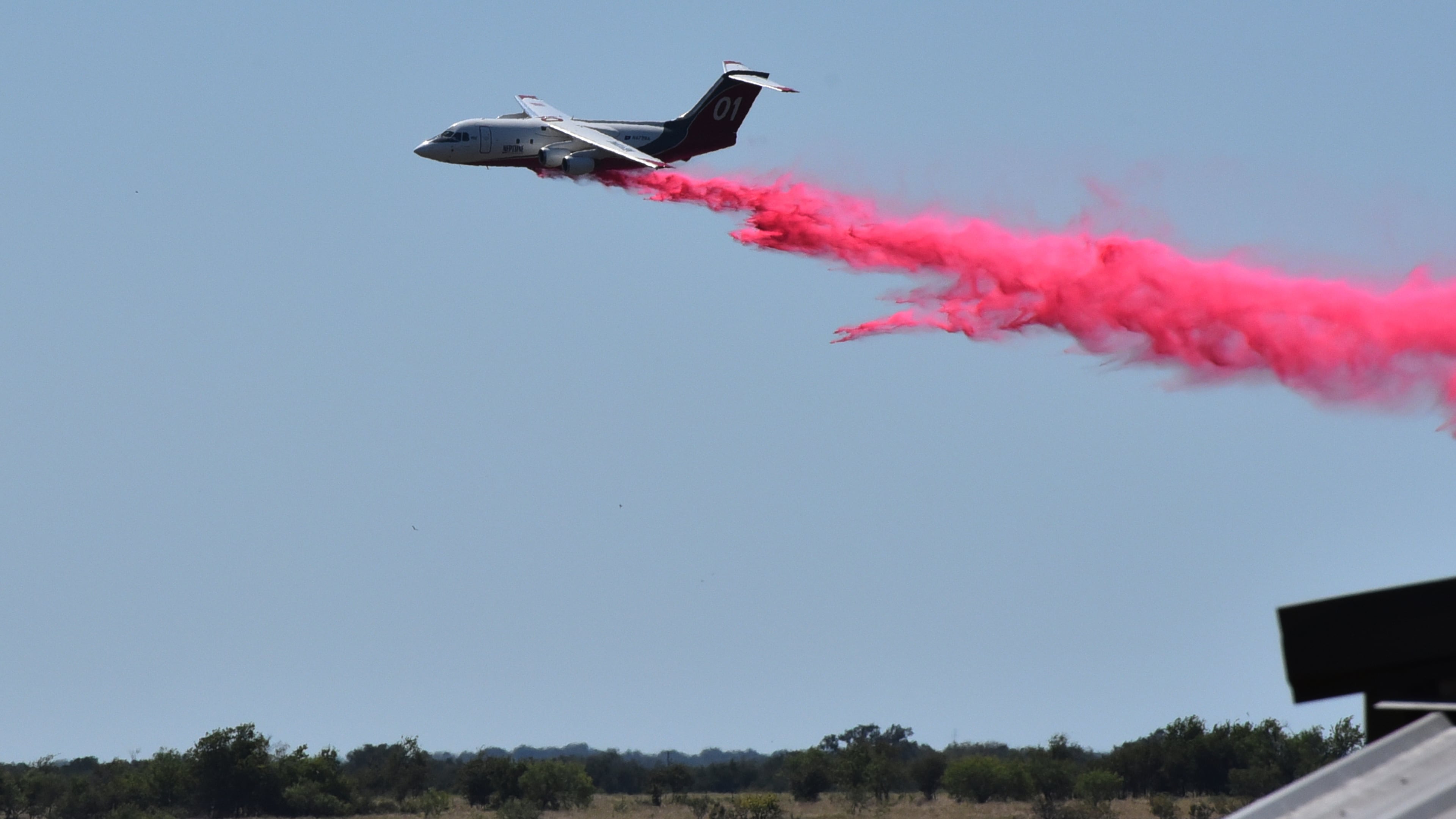 A tanker aircraft dumps fire retardant on a field southwest of Salado, Texas, Wednesday, Aug. 12, 2026, after a military helicopter crashed and sparked a grass fire. (Brent Johnson/The Killeen Daily Herald via AP)