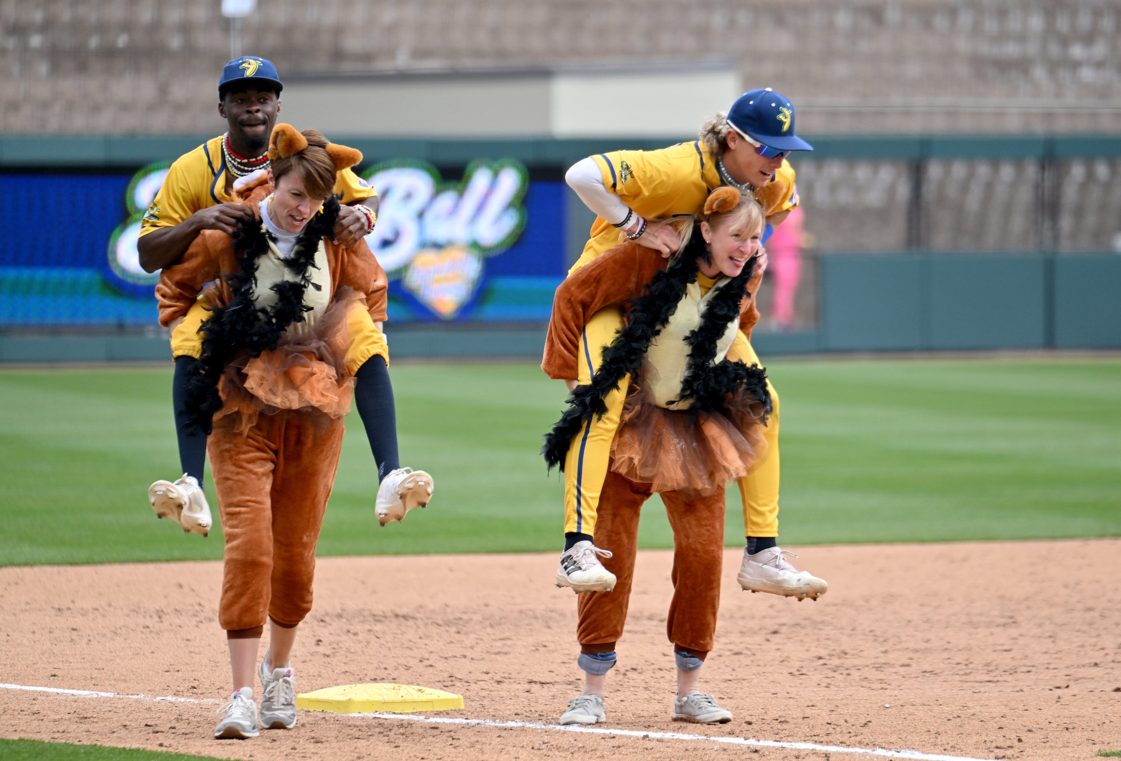 Two fans carry Savannah Bananas players around the bases. (Hyosub Shin / Hyosub.Shin@ajc.com)