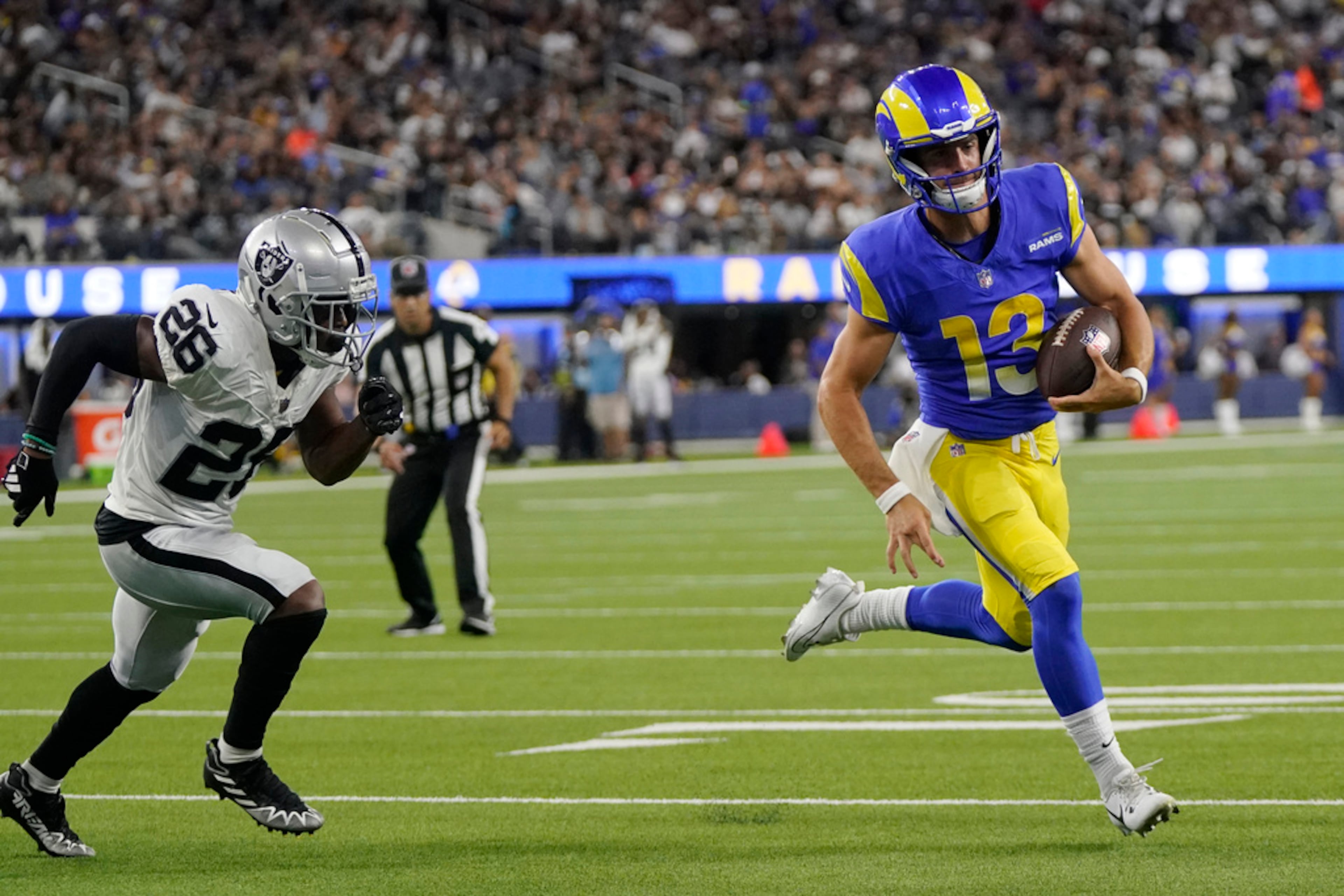 Los Angeles Rams quarterback Stetson Bennett, right, runs for a touchdown past Las Vegas Raiders safety Jaquan Johnson during the second half of a preseason NFL football game Saturday, Aug. 19, 2023, in Inglewood, Calif. The Rams lost 34-17. (AP Photo/Mark J. Terrill)