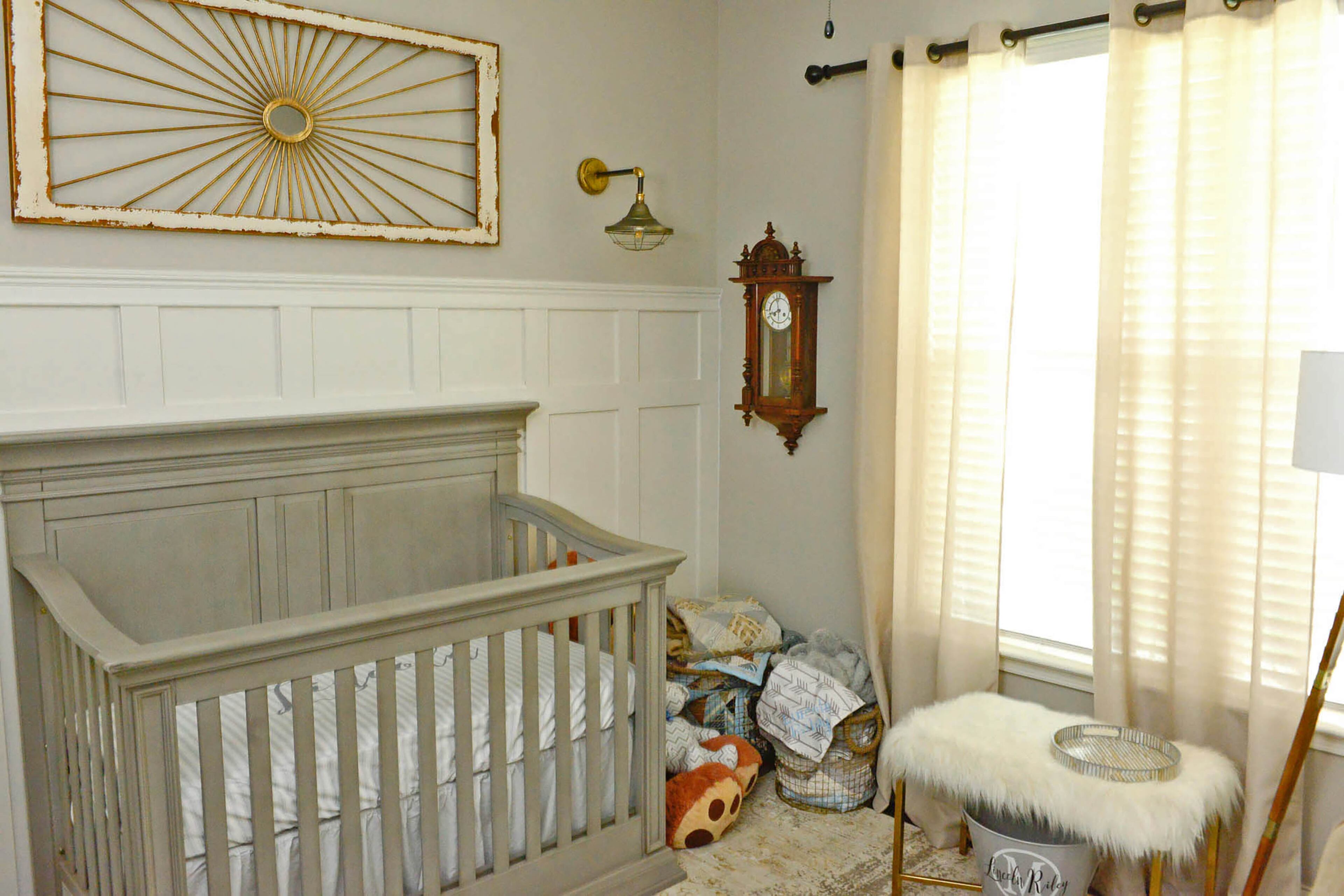 For Lincoln's nursery, Leslie McCoy chose a gray Baby Cache crib from Babies R Us set against a paneled accent wall. Brass light sconces from Ashley Furniture HomeStore highlight the metal in the art piece above his crib.