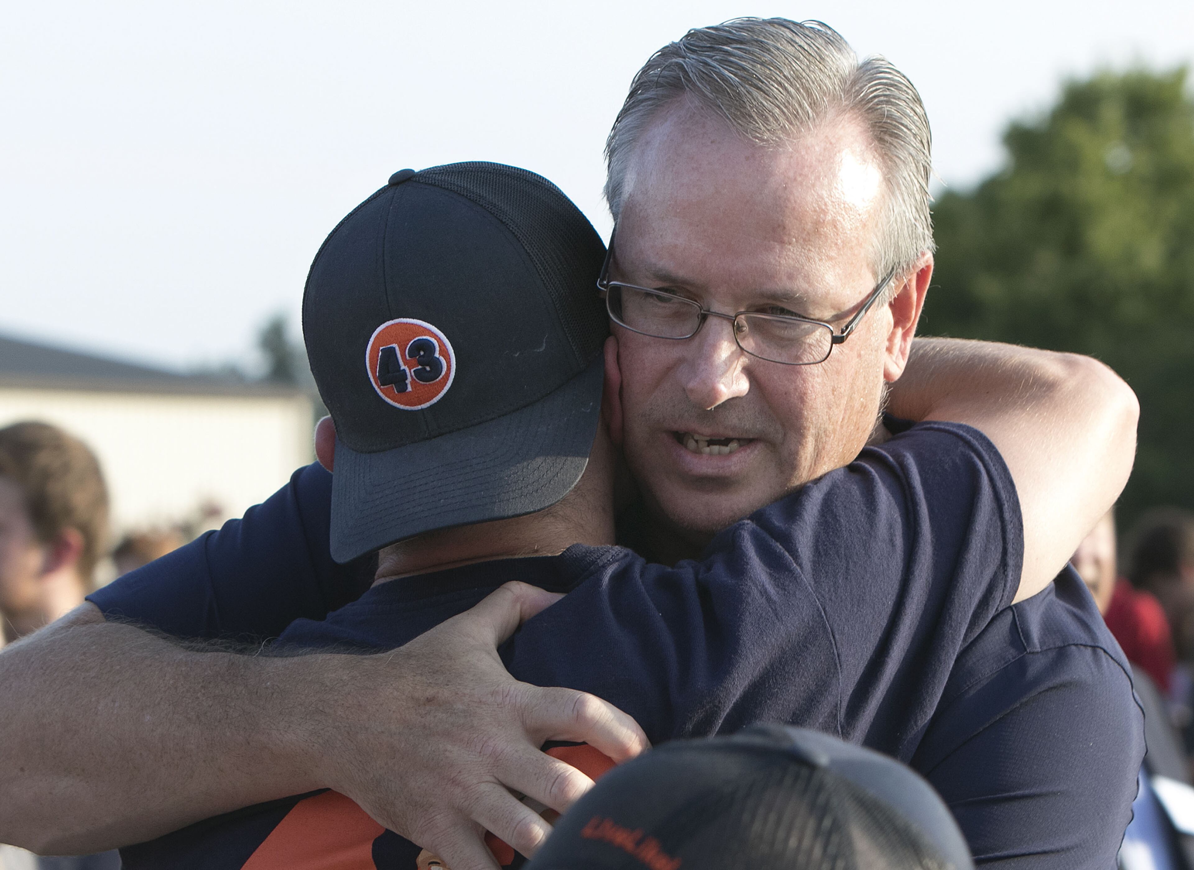 Mike Lutzenkirchen hugs a former Lassiter High football teammate of his son Philip before a dedication of the newly resurfaced and newly named Lutzie Field at Lassiter High in Marietta on Friday August 14th, 2015. (Photo by Phil Skinner)