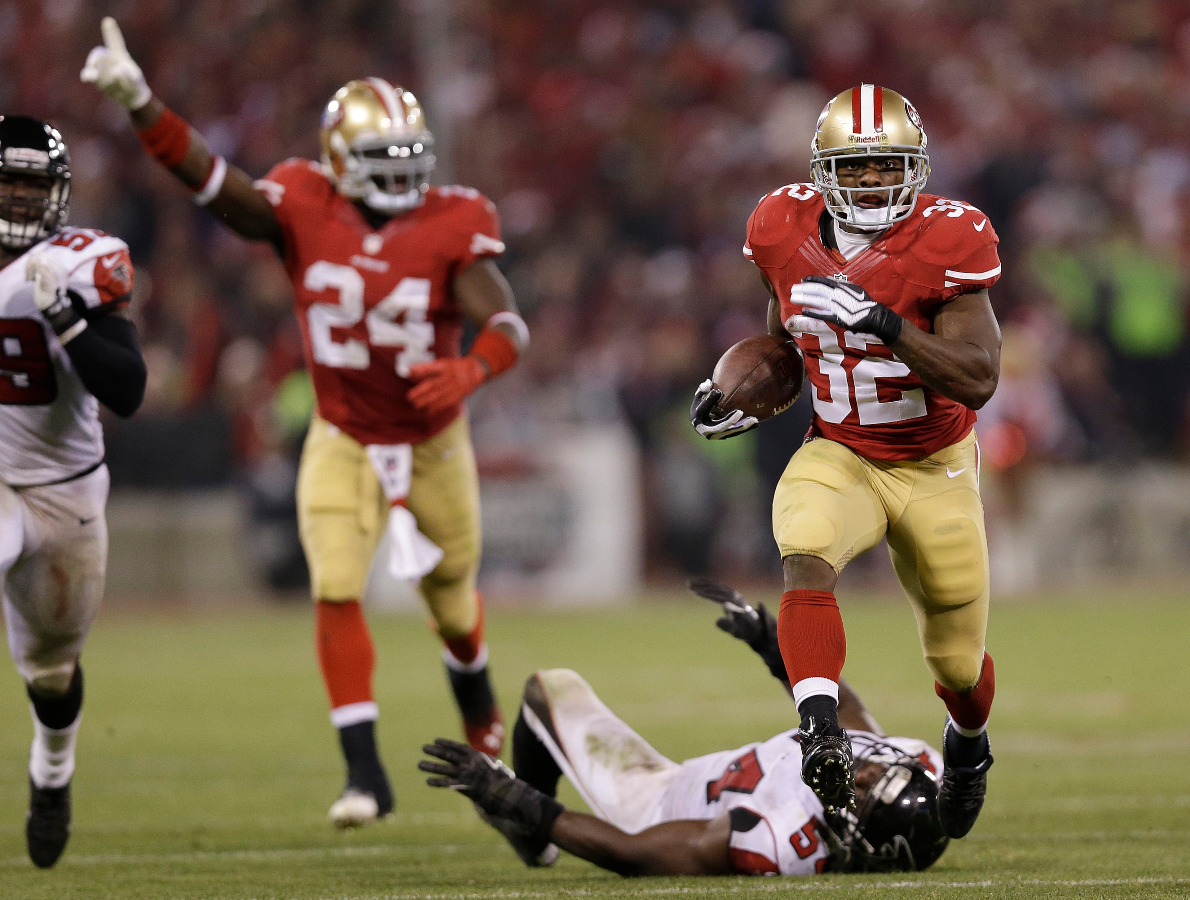 San Francisco 49ers running back Kendall Hunter (32) runs past Atlanta Falcons outside linebacker Stephen Nicholas, on ground, for a long gain as Anthony Dixon (24) celebrates during the second half of an NFL football game in San Francisco, Monday, Dec. 23, 2013. (AP Photo/Marcio Jose Sanchez)