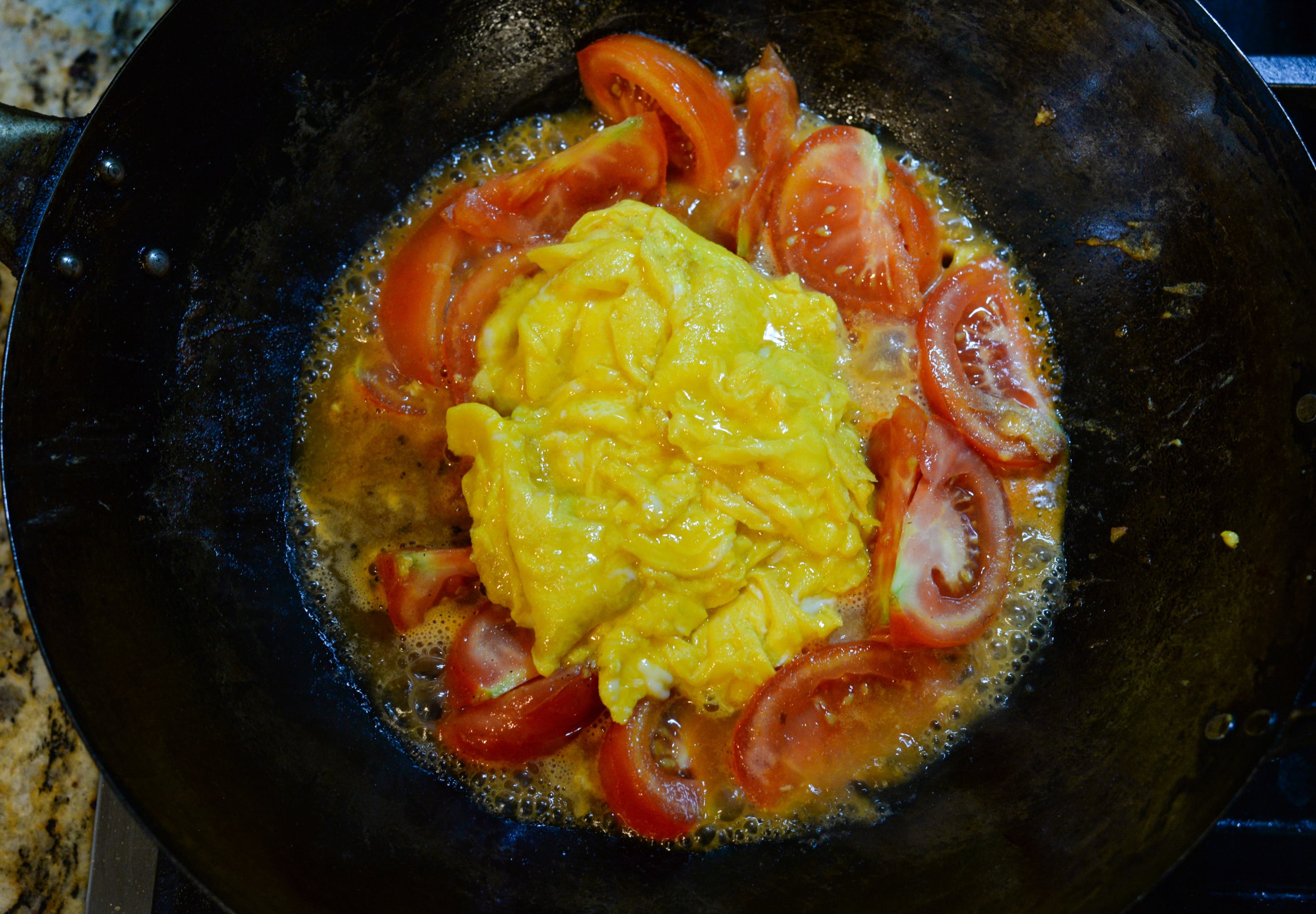 Give the chicken broth mixture a stir to reincorporate the cornstarch, then immediately pour it over the tomatoes. Return the eggs to the wok. Cover the wok with a lid and cook for 2 minutes. (Candy Hom for the AJC)