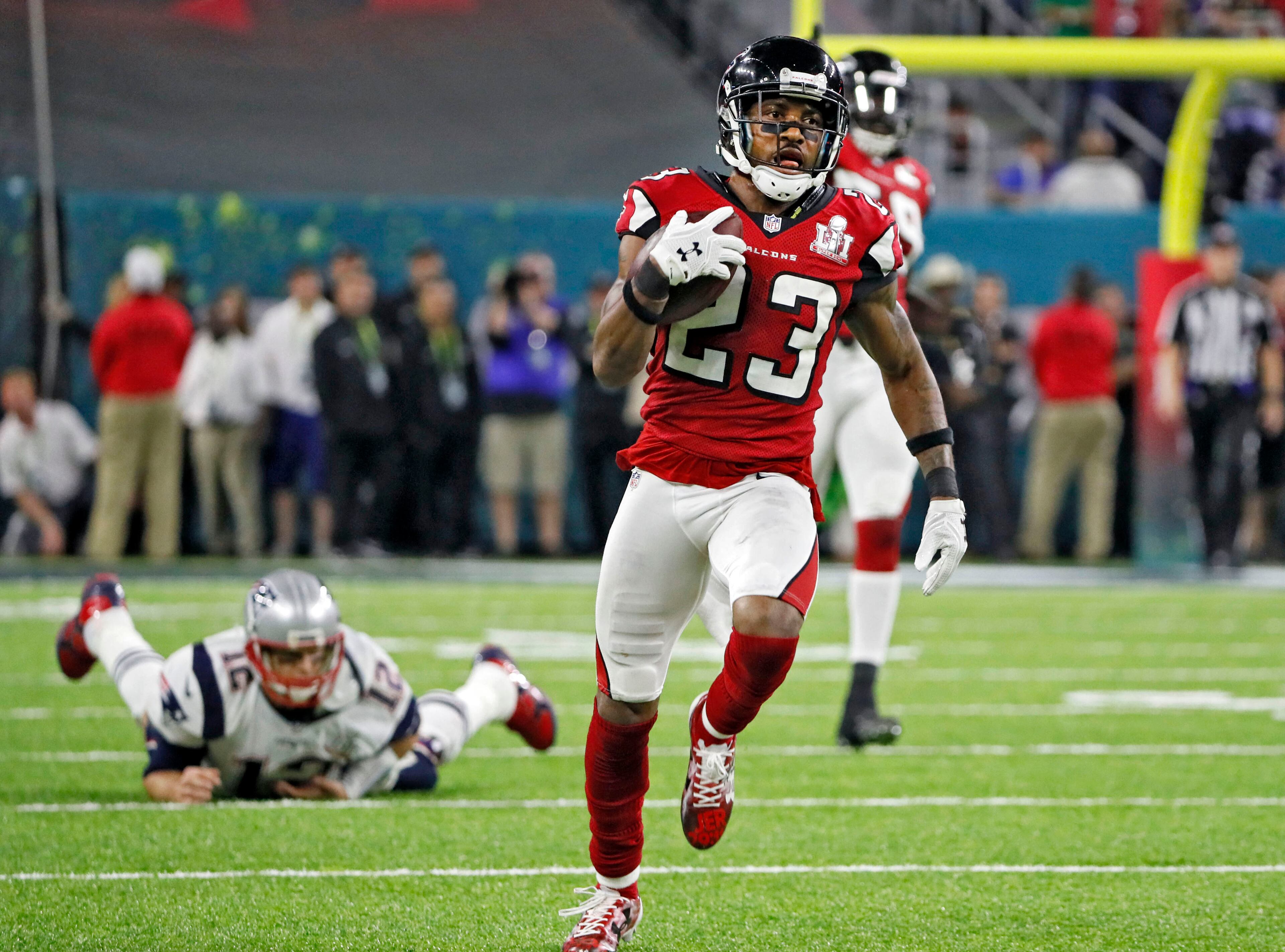 With Patriots quarterback Tom Brady watching in the background, Falcons cornerback Robert Alford heads toward the end zone with an 82-yard interception return that gave the Falcons a 21-0 lead in the second quarter. Bob Andres/AJC