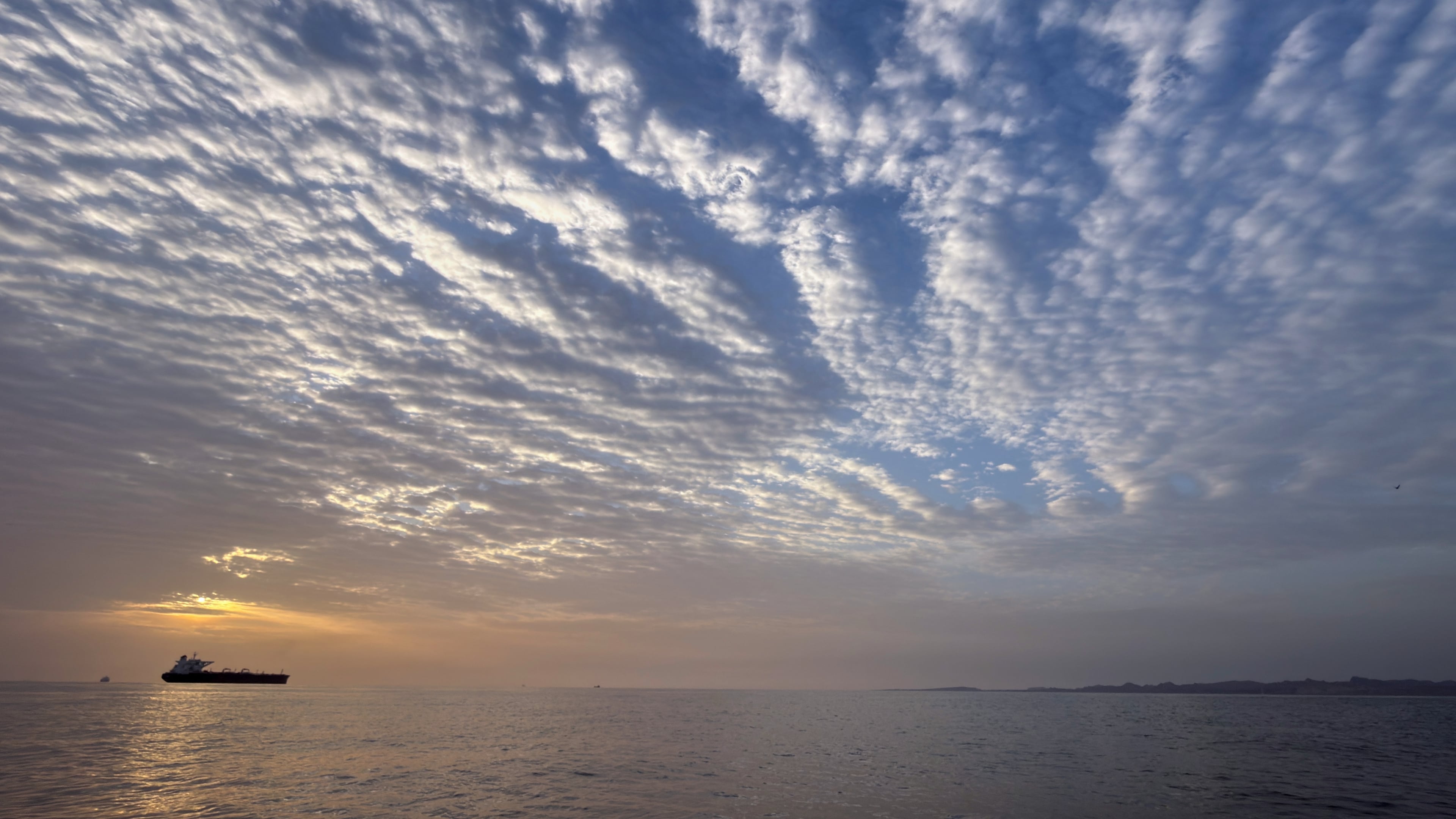 The sun rises behind a tanker anchored in the Strait of Hormuz off the coast of Qeshm Island, Iran, Saturday, April 18, 2026. (AP Photo/Asghar Besharati)