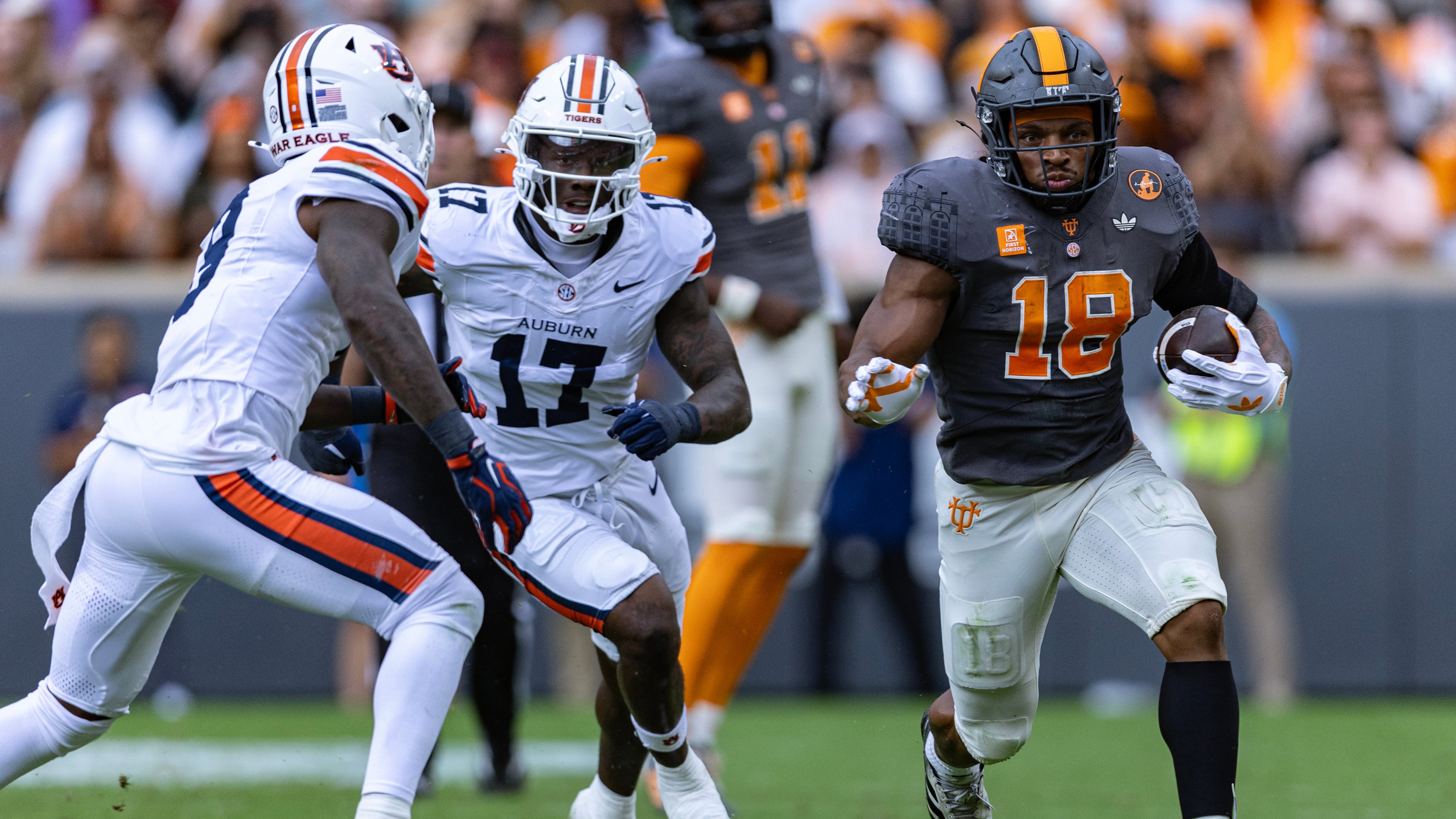 Tennessee running back DeSean Bishop (18) runs for yardage as he is chased by Auburn linebackers Xavier Atkins (17) and Elijah Melendez, left, during the first half of an NCAA college football game Saturday, Oct. 3, 2026, in Knoxville, Tenn. (AP Photo/Wade Payne)