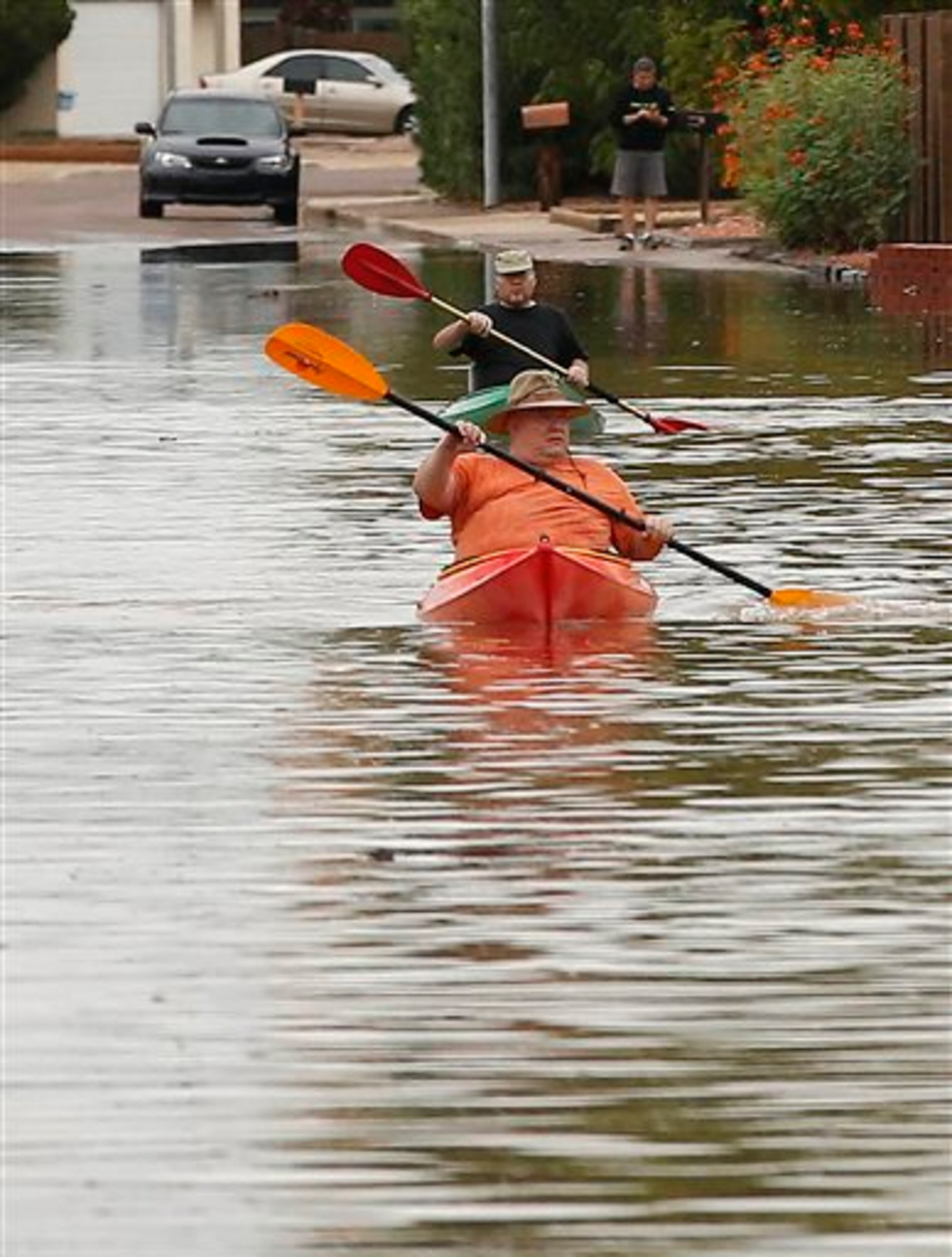 Two residents of a Chandler neighborhood canoe down a flooded street after record breaking rains closed streets, highways and schools Monday, Sept. 8, 2014, in Chandler, Ariz. (AP Photo/Darryl Webb)