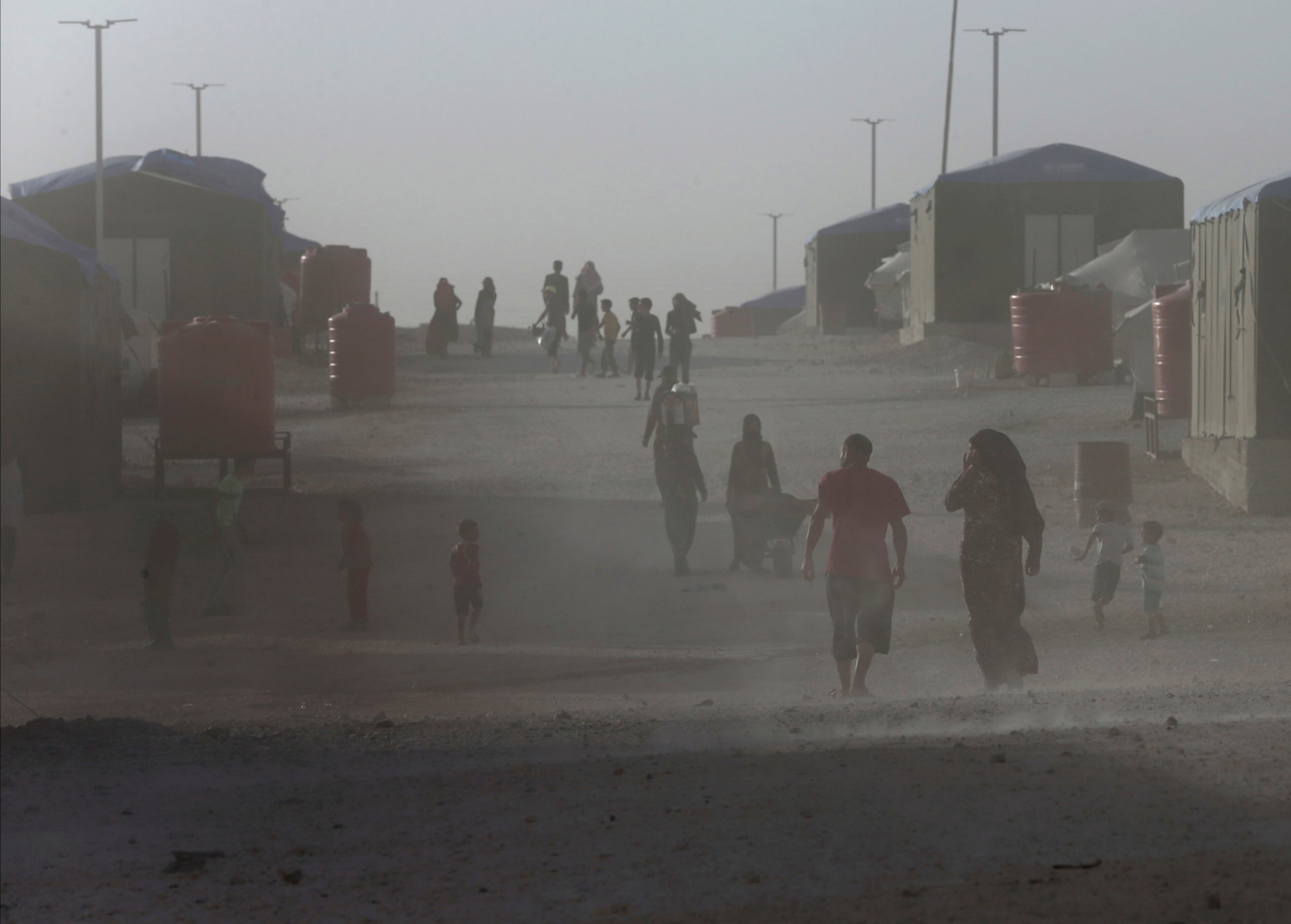 Syrian displaced people who fled the battle between U.S.-backed Syrian Democratic Forces and the Islamic State militants from Raqqa city, walk in the dust at a refugee camp, in Ain Issa town, northeast Syria, Wednesday, July 19, 2017. The U.S. military is supporting local Syrian forces in a campaign to drive IS from Raqqa.(AP Photo/Hussein Malla)