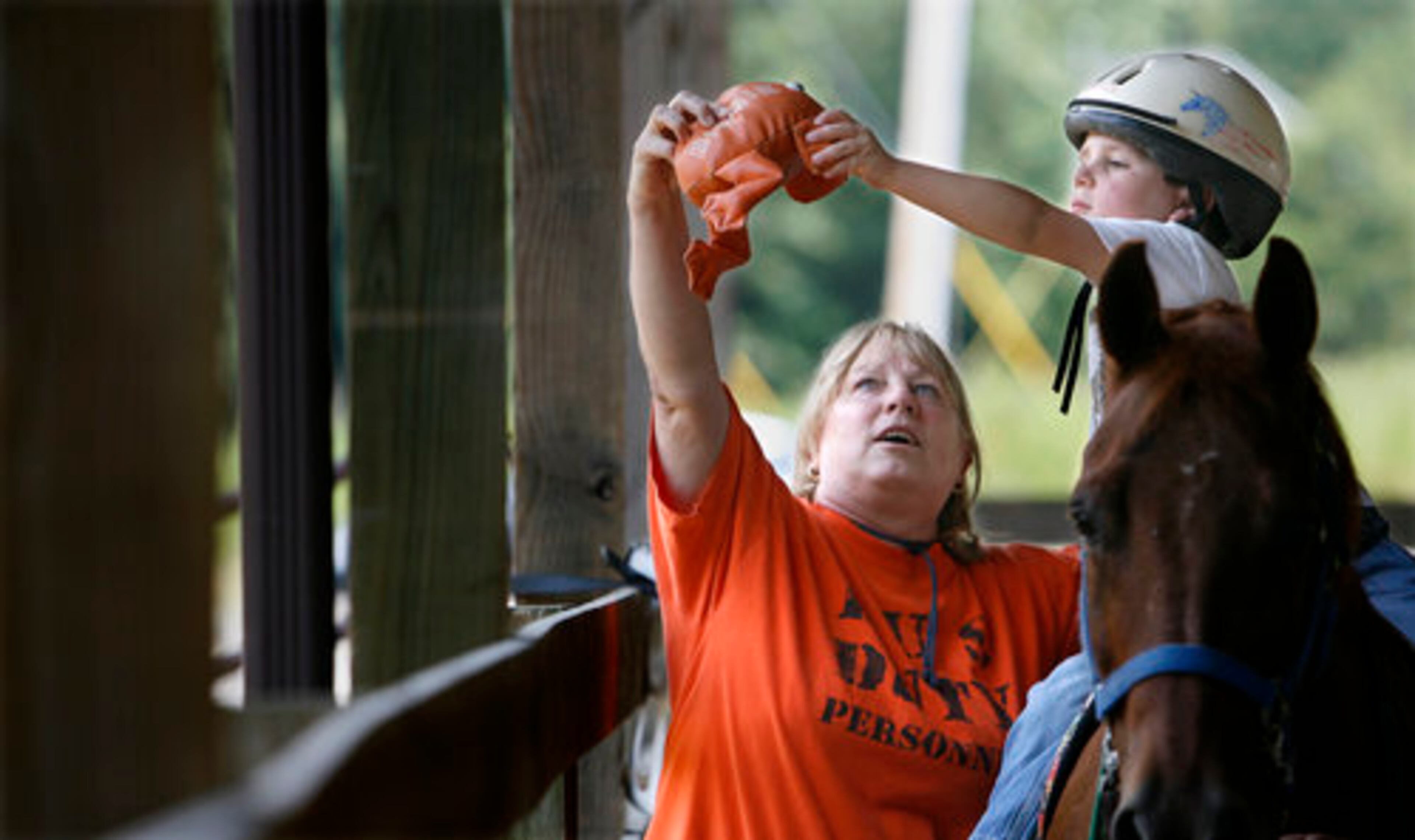 Cole Simonds, 5 1/2, of Lilburn, reaches over to grab a beanie frog from volunteer Terry Allen during a therapeutic ride at Parkwood Farms Therapy Center on Thursday. The center provides therapy for children with special needs including autism, Downs' Syndrome, Cerebral Palsy, emotional problems and learning disabilities.